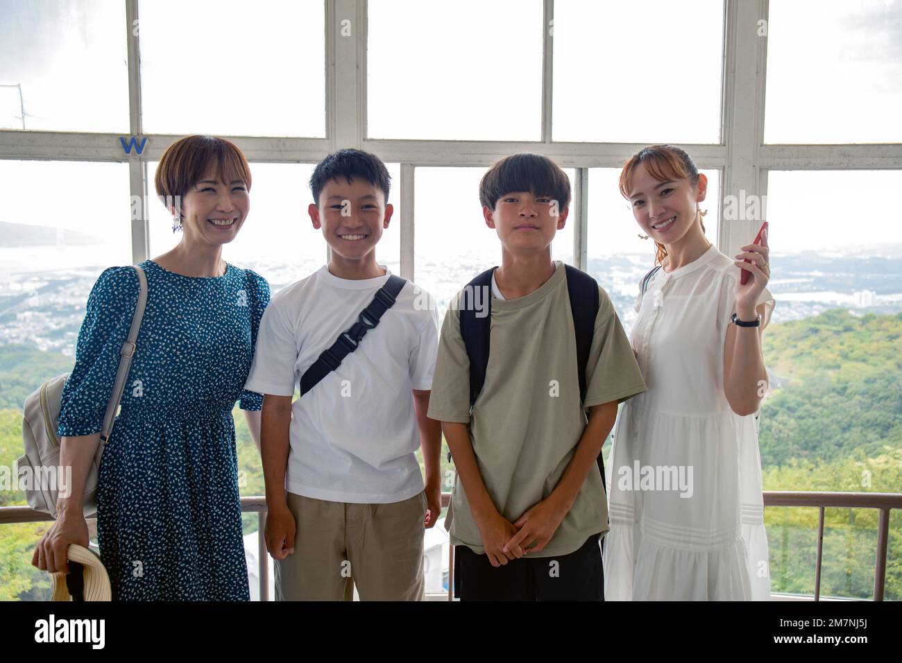 Vier Japaner, zwei Jungen und zwei reife Frauen an einem Tag, posieren für ein Foto, Seite an Seite, auf einer Aussichtsplattform. Stockfoto