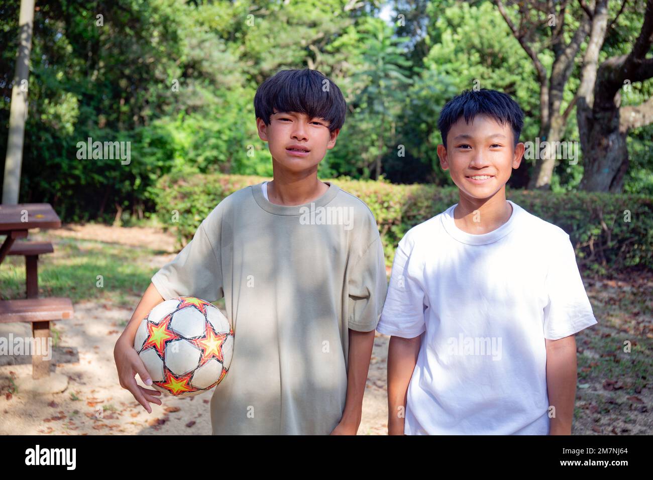 Zwei 13 Jahre alte Jungs in einem Park mit einem Fußball im Sommer. Stockfoto