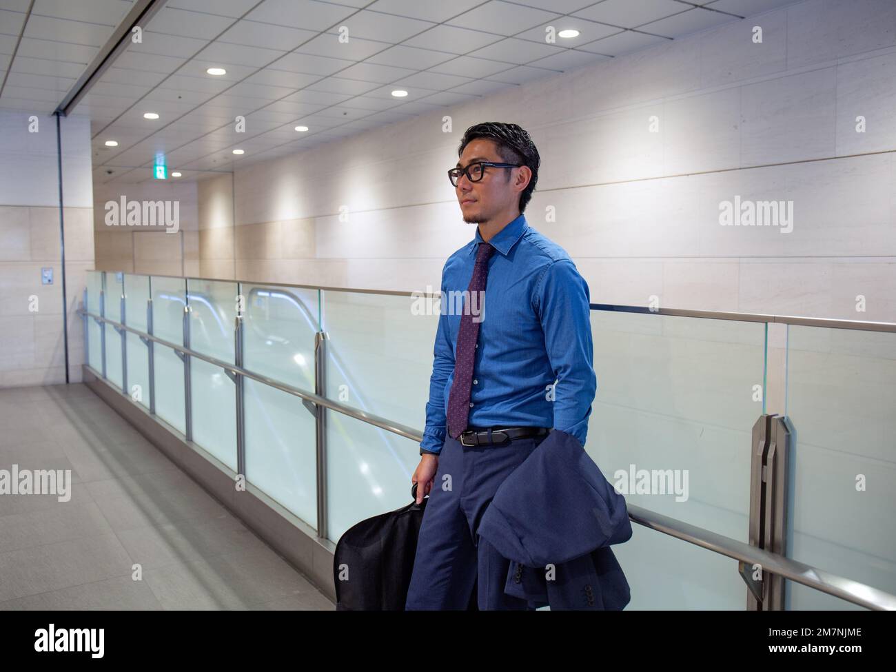 Ein junger Geschäftsmann in der Stadt, auf dem Weg, mit einer Laptop-Tasche und einem Mantel. Stockfoto