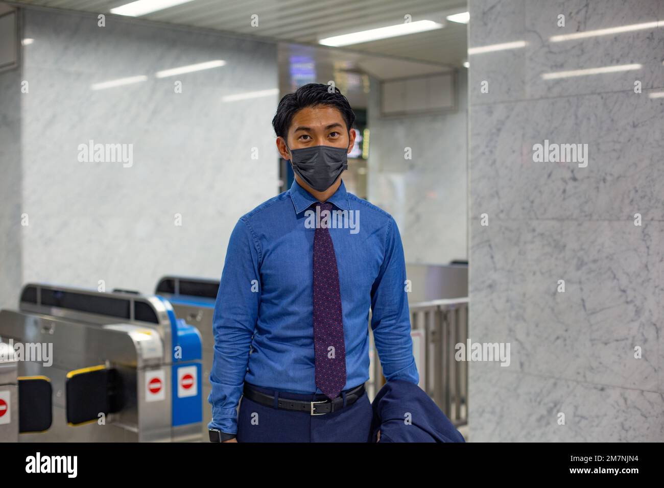 Ein junger Geschäftsmann in der Stadt, unterwegs, trägt eine Gesichtsmaske. Stockfoto