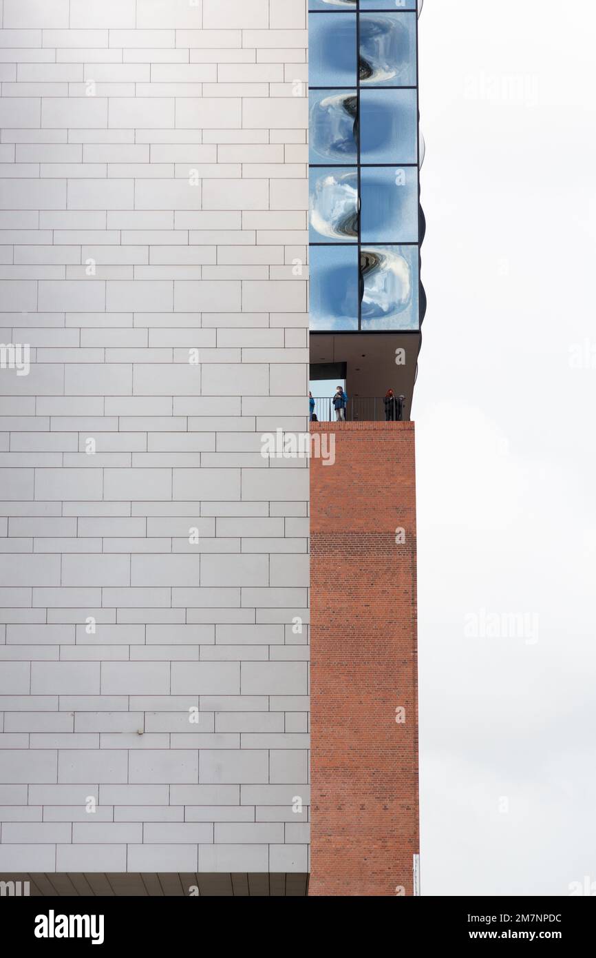 Die Fassade der Elbphilharmonie blickt mit einem kleinen Streifen hinter einer weißen Klinkerfassade hervor. Stockfoto