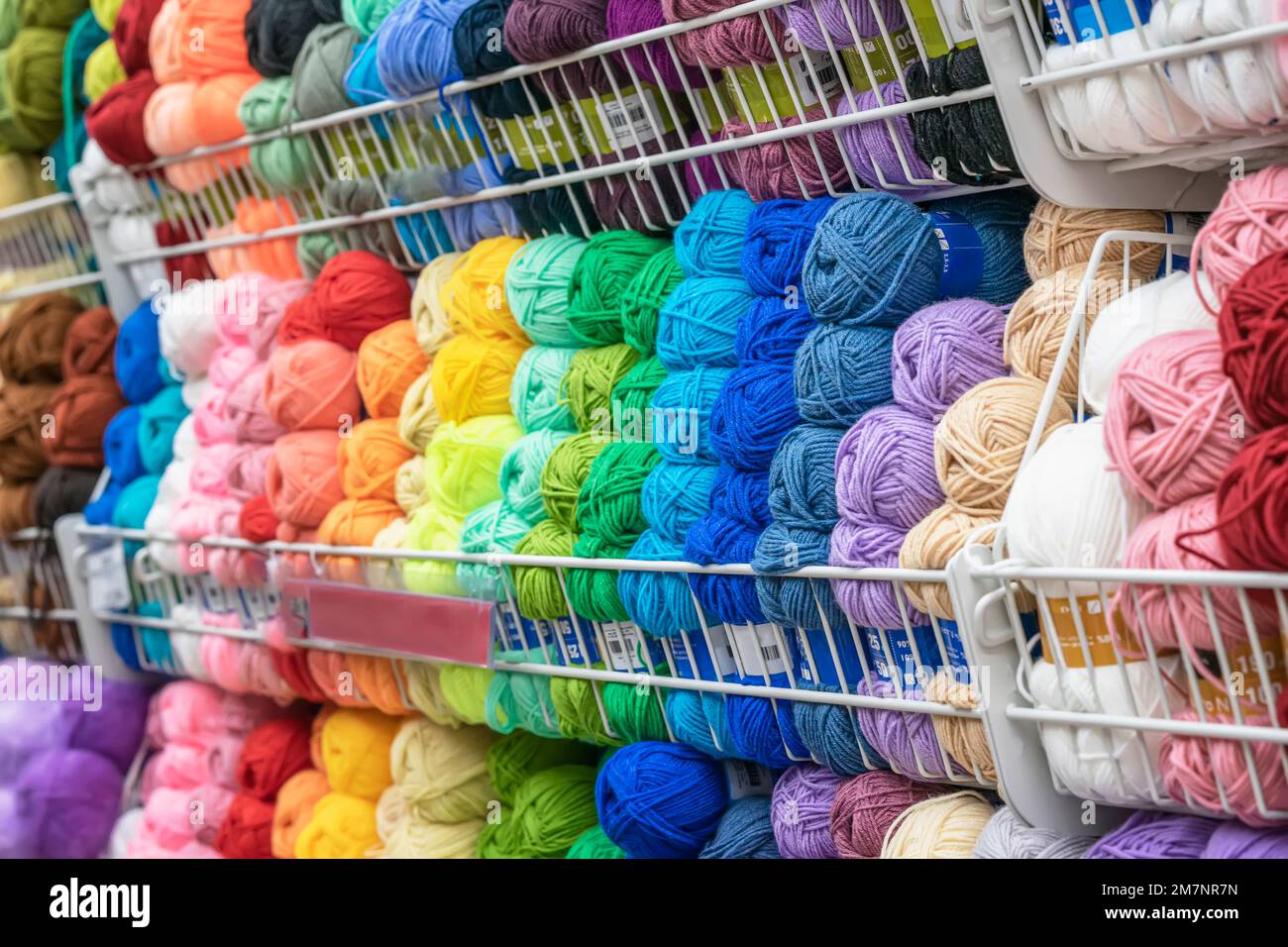 Verschwommener abstrakter Hintergrund des Stores mit farbenfrohem Garn zum Stricken. Vorratslager für Kreativität, Handarbeit, Hobby Stockfoto