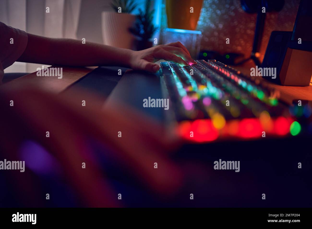 Nahaufnahme Handaufnahme eines Spielers beim Drücken der Tasten auf der Tastatur während eines Online-Videospiels. Tastatur-Led-Leuchten. Der Raum ist dunkel. Stockfoto