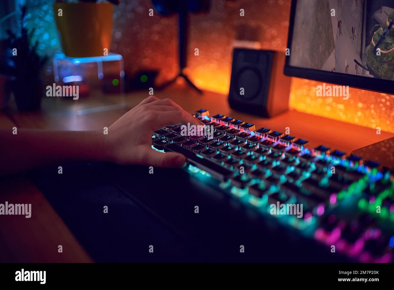 Nahaufnahme Handaufnahme eines Spielers beim Drücken der Tasten auf der Tastatur während eines Online-Videospiels. Tastatur-Led-Leuchten. Der Raum ist dunkel. Stockfoto