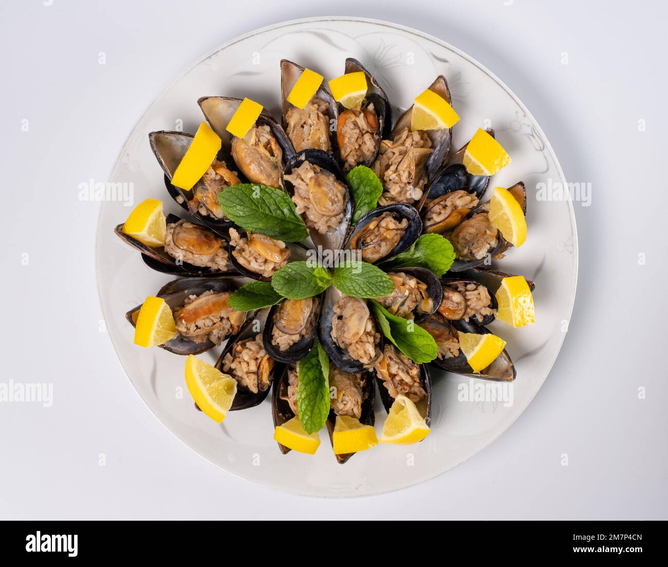 Top View Türkisches Street Food gefüllte Muscheln und Zitrone auf Teller isolierter weißer Hintergrund. Schwarze Schalentiere für Banner, Katalog oder Menü. Stockfoto