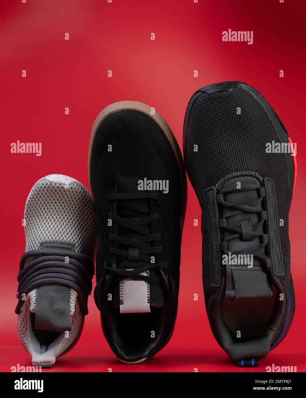 Sneakerschuhe in verschiedenen Größen über der oberen Ansicht isoliert auf rotem Studiohintergrund Stockfoto