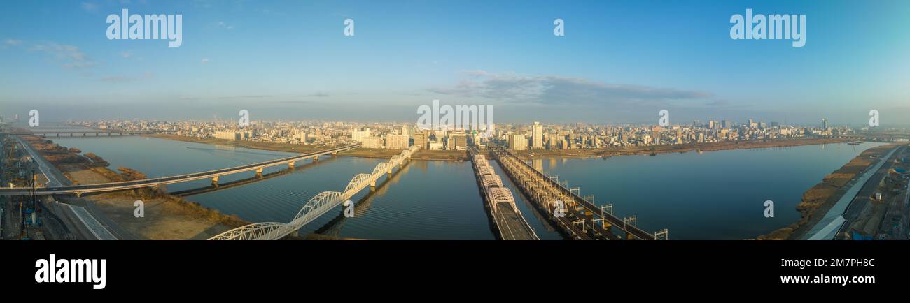 Panoramablick auf Brücken über den breiten Fluss bis zur weitläufigen Stadt am frühen Morgen Stockfoto