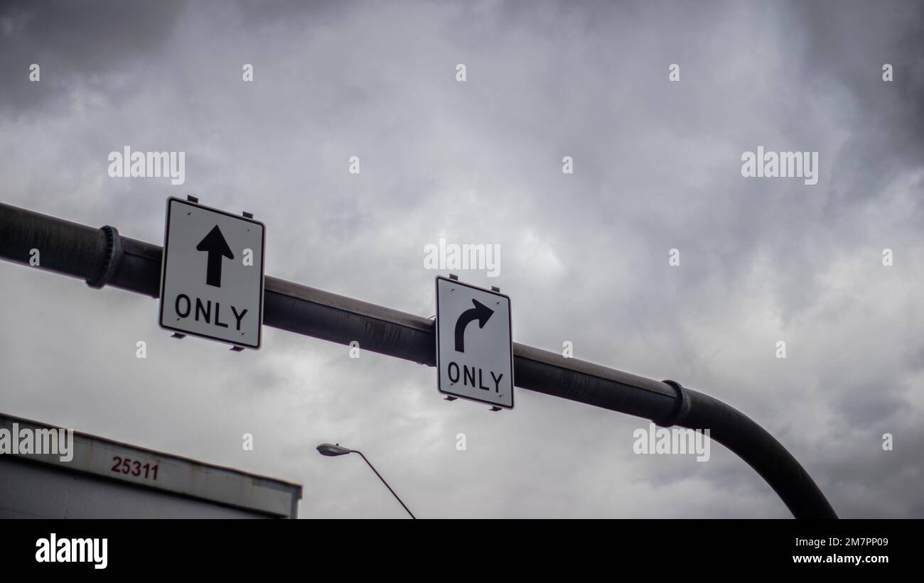 Eine graue Straßenkonstruktion, die nur aus Vorwärtsfahrten und nur Rechtskurven besteht und im Hintergrund Wolken aufweist Stockfoto