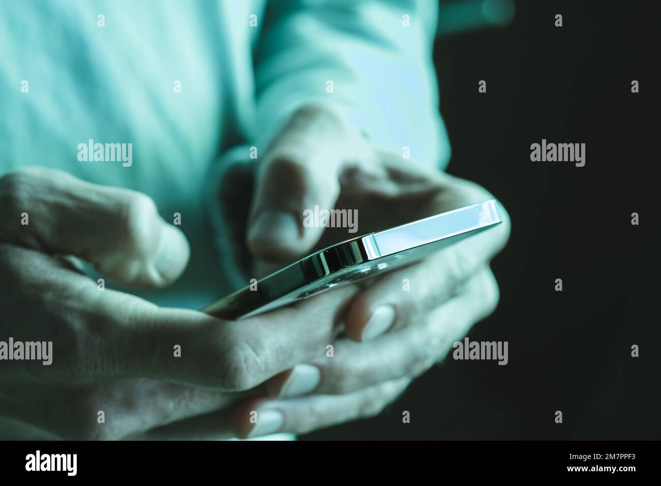 Mann, der mit dem Handy Text schreibt oder soziale Medien in Neonlichtern überprüft. Stockfoto