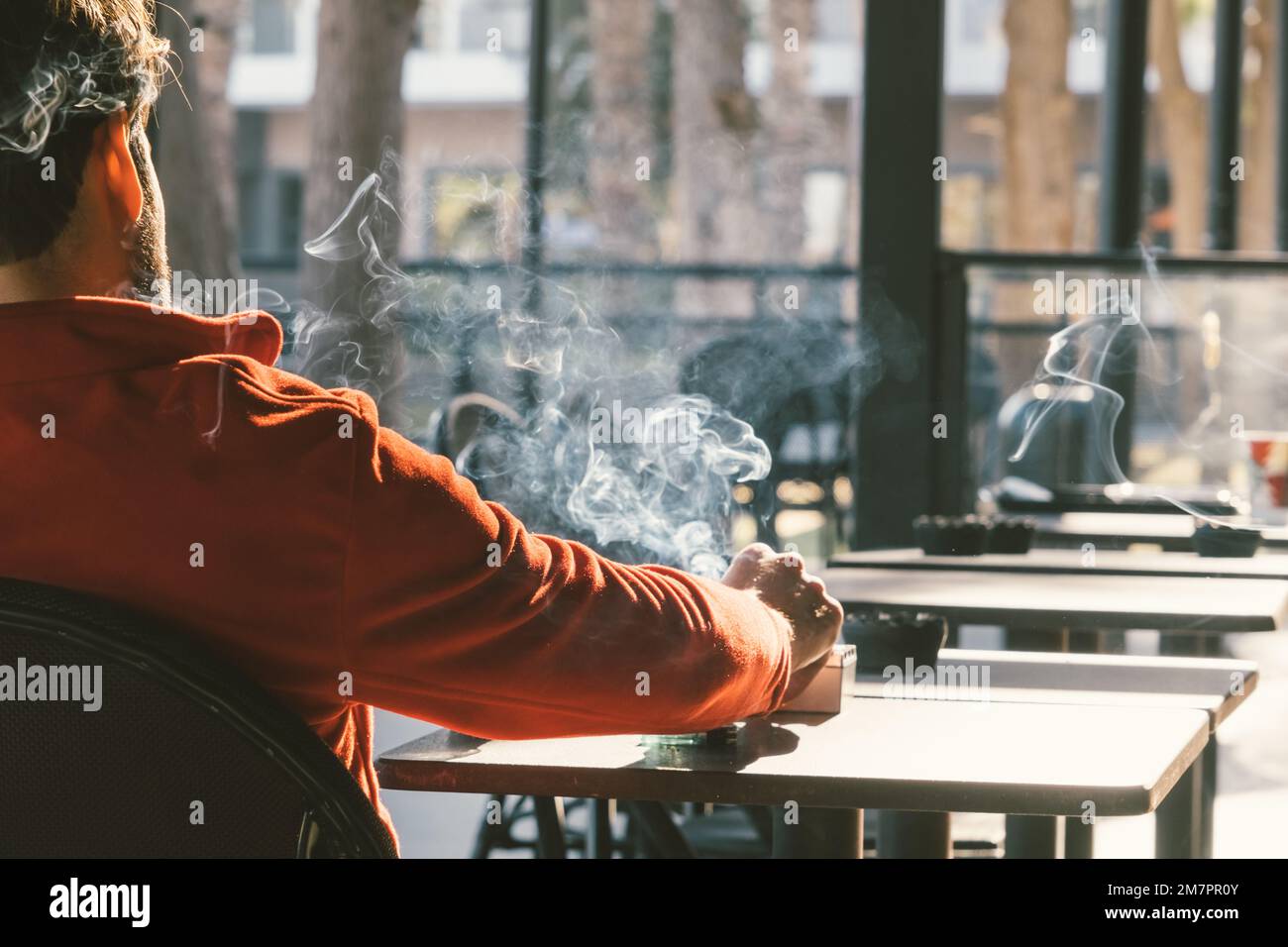 Rückblick auf einen Mann, der im Café Zigaretten raucht. Ungesunder Lebensstil. Stockfoto