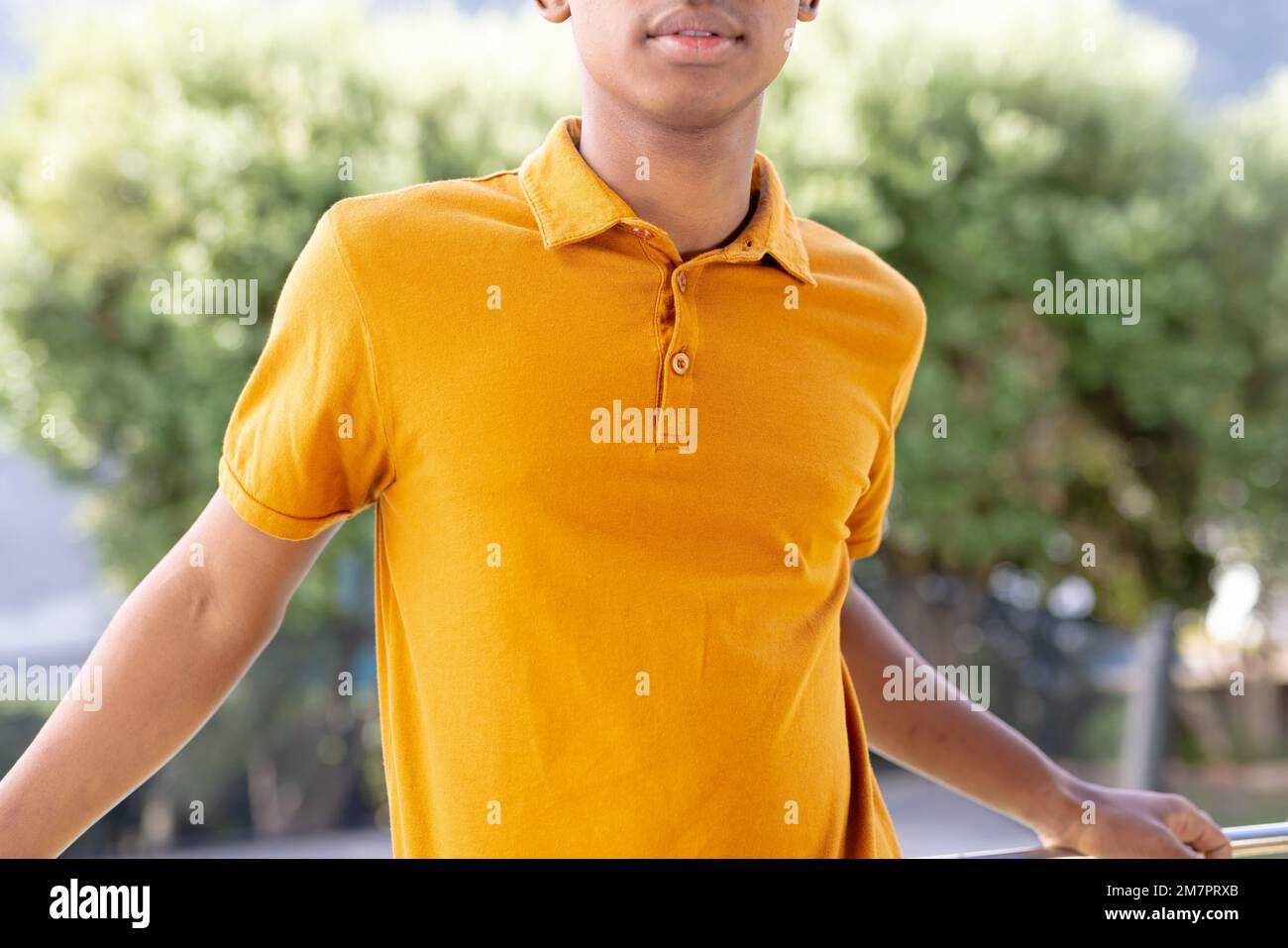 Bild eines birassischen Mannes im orangefarbenen Kurzarm-Polo-T-Shirt mit Kopierraum Stockfoto