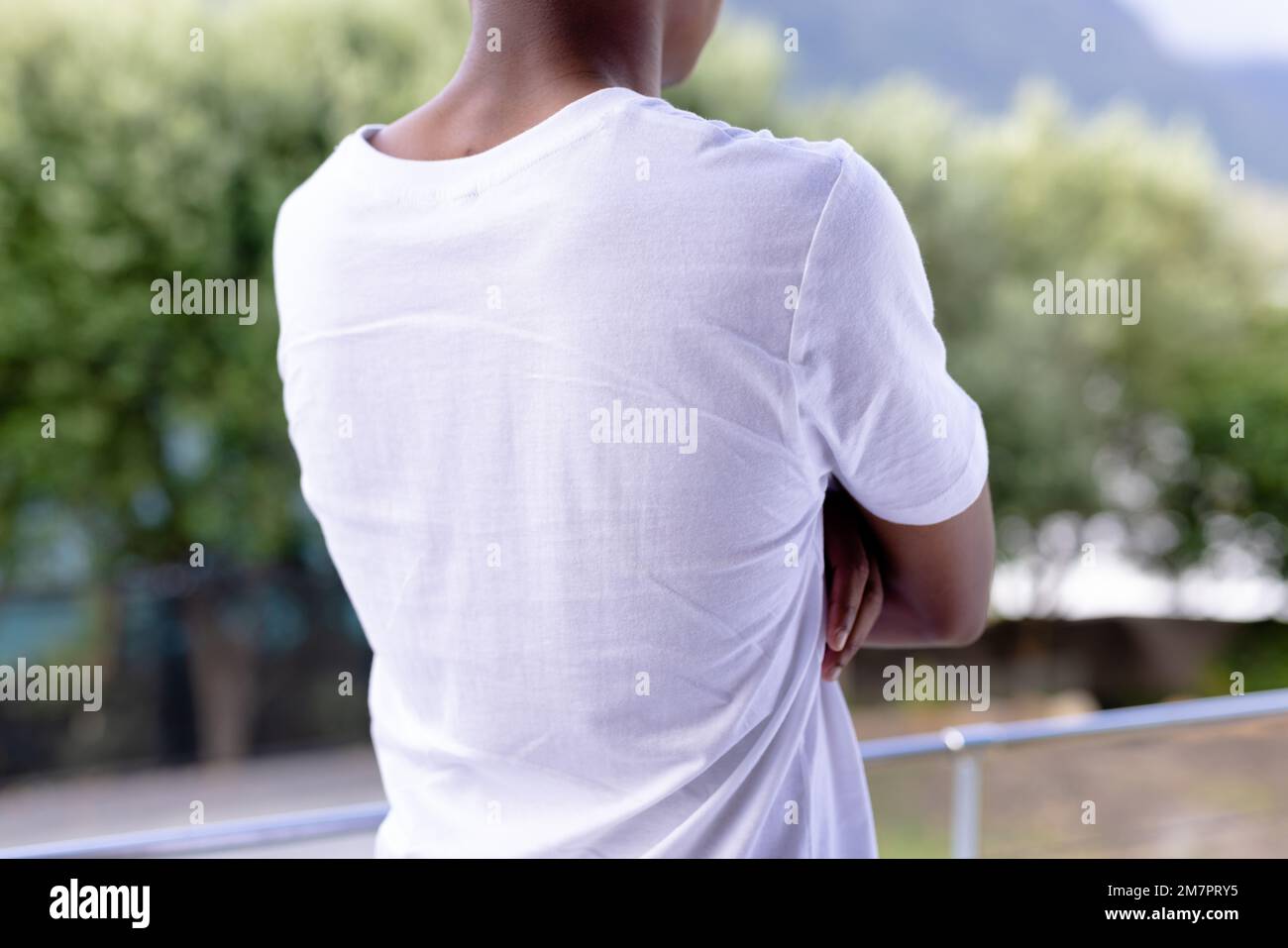 Bild eines afroamerikanischen Mannes in einem weißen Kurzarm-T-Shirt mit Werbeträgern über Bäumen im Hintergrund Stockfoto