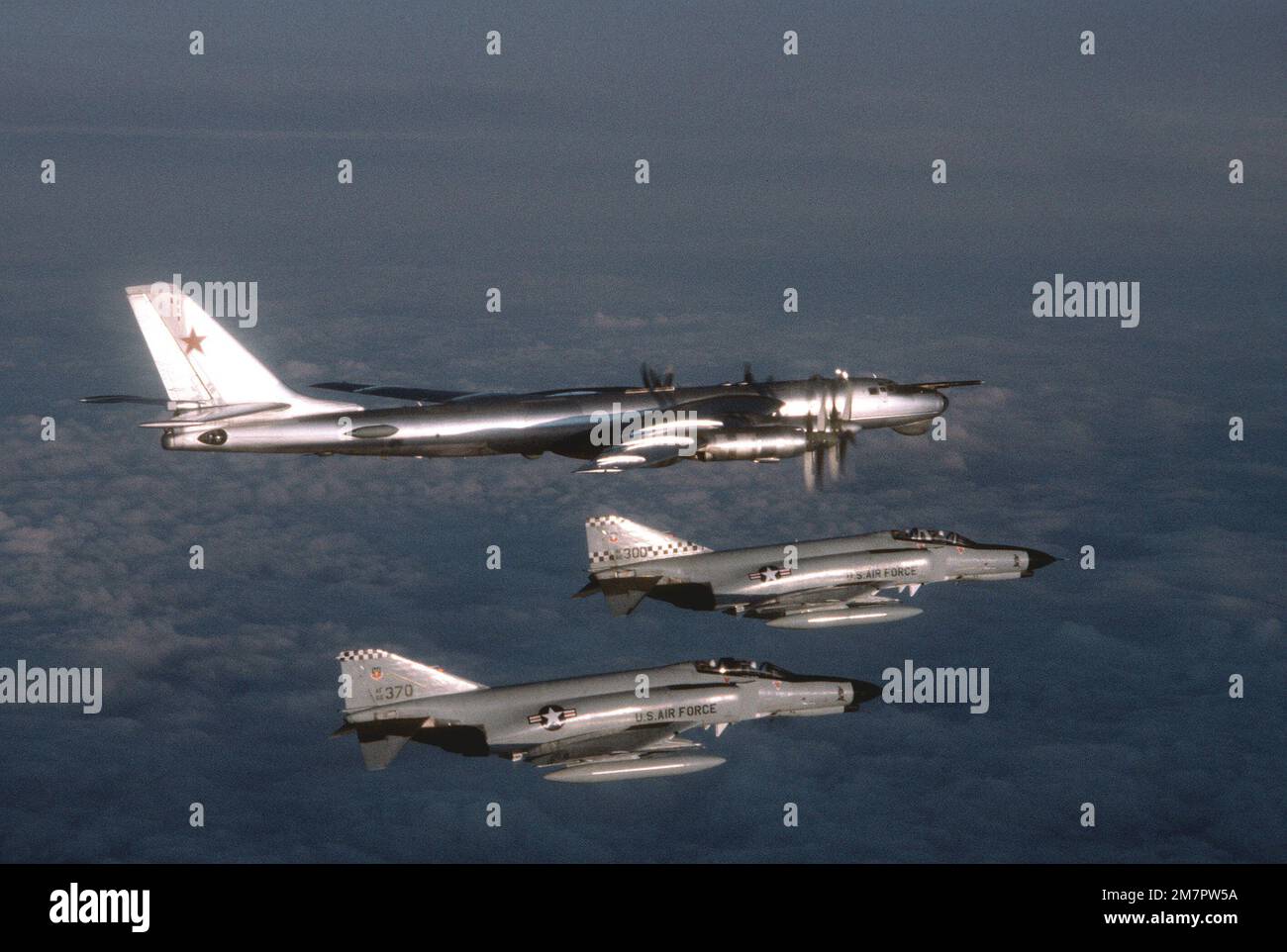 Eine Air-to-Air-Ansicht von rechts auf ein sowjetisches TU-95 Bear-Flugzeug, oben, beobachtet von zwei US-Bürgern Air Force F-4 Phantom II über internationalen Gewässern. Land: Nordatlantik Stockfoto