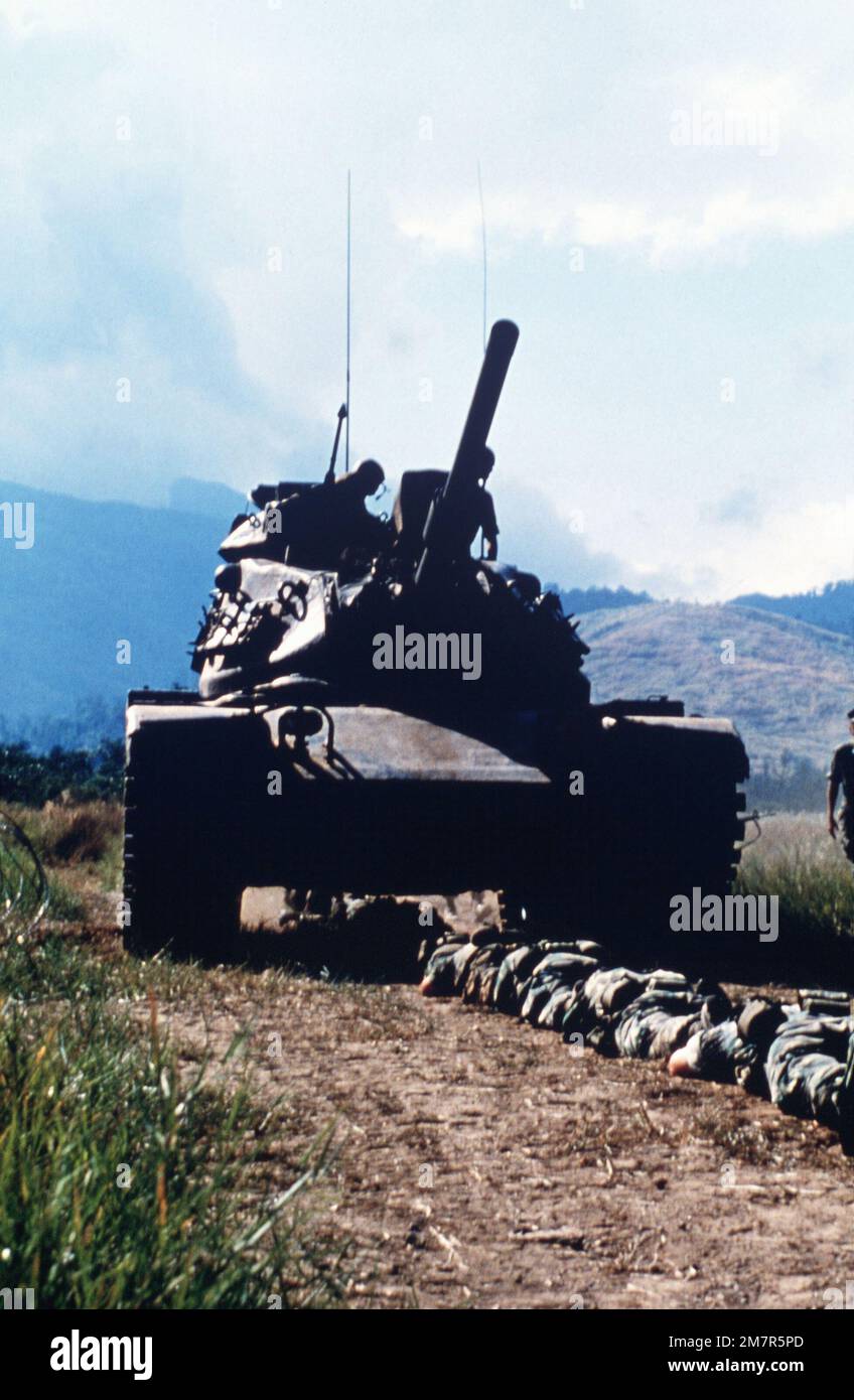 Marine Corps Infanterie- und M60A1-Panzer, die Unternehmen B, 1. Bataillon, 3. Marines (Bataillon Landing Team 1/3), 3. Marine Division, Fleet Marine Force (FMF) bilden, absolvieren eine Woche lang Training im Zambolies Training Area während ihrer Westpazifik (WESTPAC) Kreuzfahrt. Die Marines liegen auf dem Boden, während ein Panzer sie überquert. Die Panzer sind von der 1. Marine Division, FMF. Land: Philippinen (PHL) Stockfoto