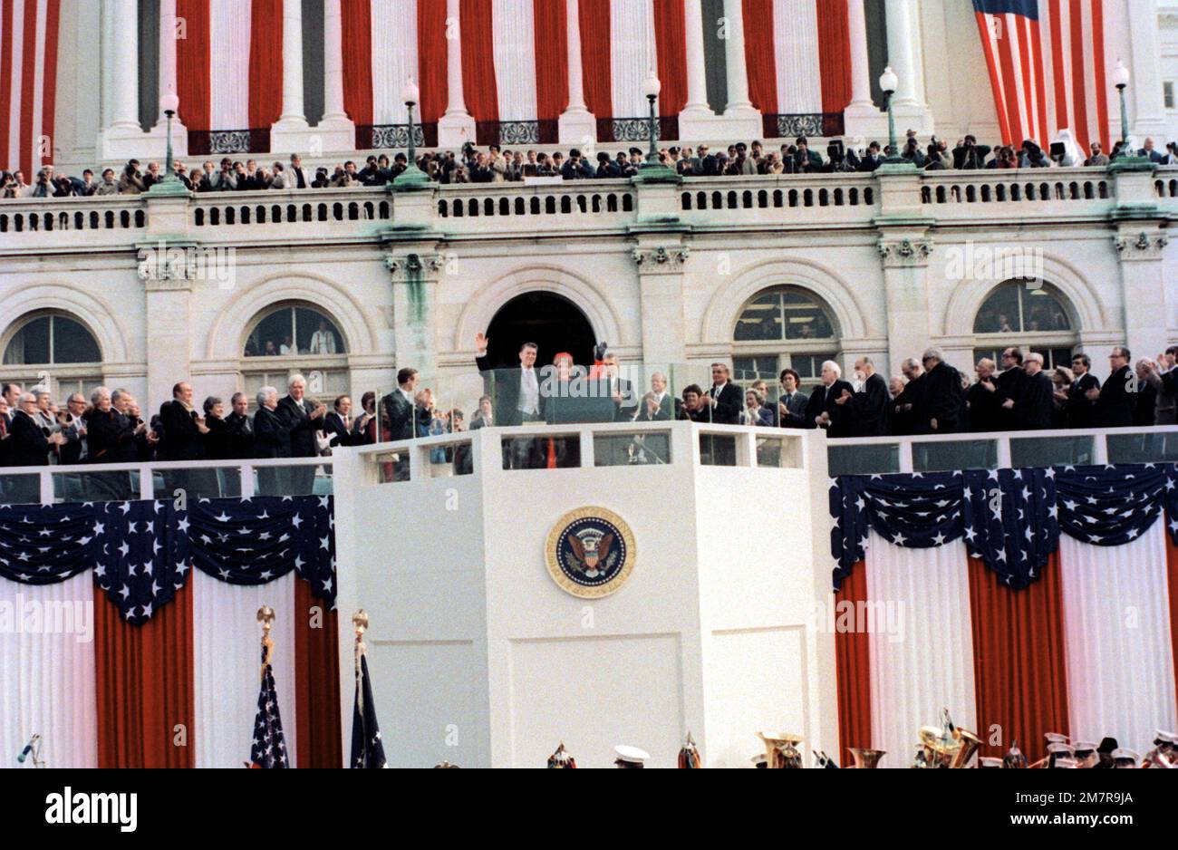 Am Ende der Eröffnungsrede von Präsident Ronald Reagan winken er und seine Frau Nancy während der Feier des Eröffnungsfeiertages von der speziell gebauten Plattform vor dem Kapitol der Öffentlichkeit zu. Basis: Washington State: District of Columbia (DC) Land: Vereinigte Staaten von Amerika (USA) Stockfoto