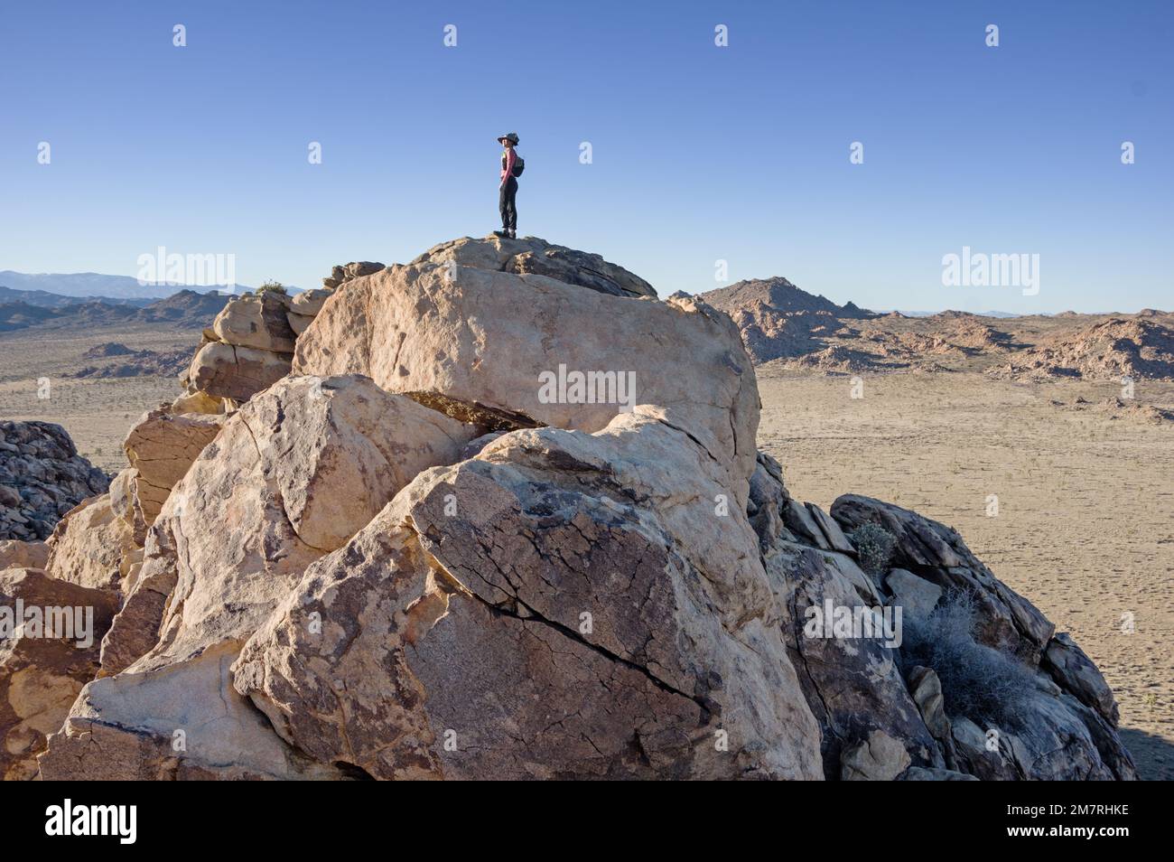 Frau auf einem felsigen Berggipfel im Joshua Tree National Park Stockfoto