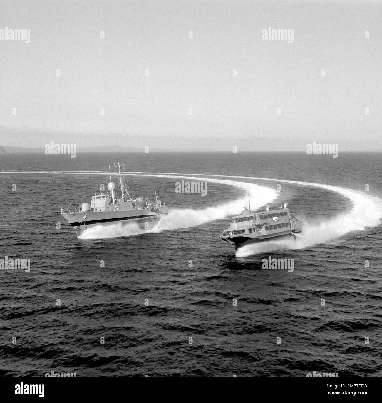 Backbordbogenansicht des Guided Missile Combatant (Tragflächenboot) AQUILA (PHM-4), links, und des Jetfoils BIMA SAMUDERA I, der während der Tests vor der Küste Seattles gemeinsam eine Rechtskurve macht. Die beiden Schiffe werden von Boeing Marine Systems gebaut. Die AQUILA wird mir in den USA geliefert Die Marine wird im Dezember 1981 und die BIMA SAMUDERA I Anfang 1982 der Marine der Republik Inodonesien beitreten. Basis: Puget Sound Bundesstaat: Washington (WA) Land: Vereinigte Staaten von Amerika (USA) Stockfoto
