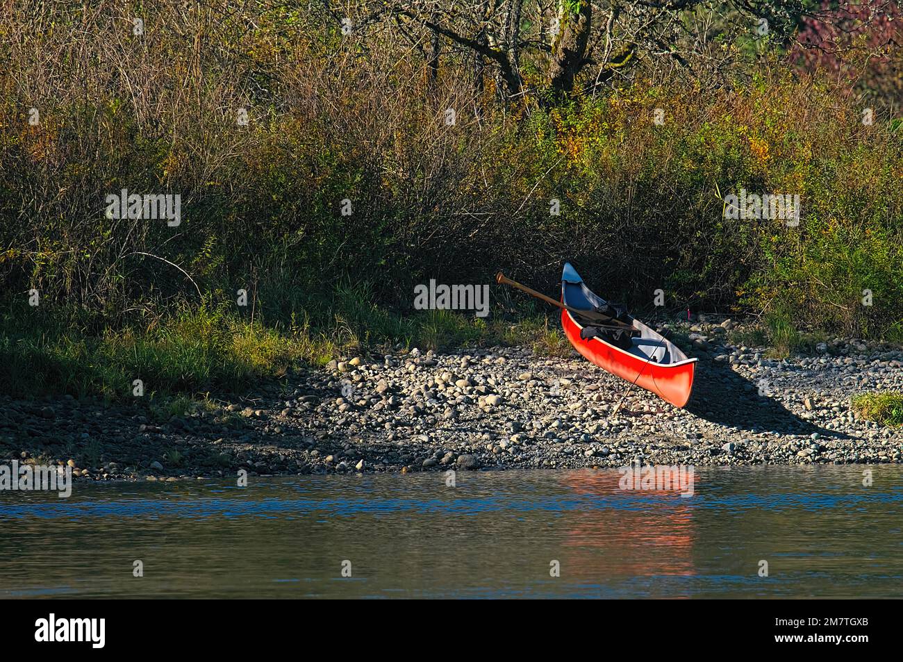 Rotes Kanu an einer felsigen Küste mit Paddeln und Angelrute. Metro Vancouver, British Columbia, Kanada. Stockfoto