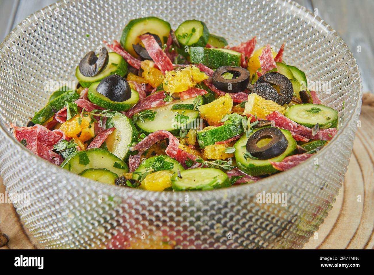 Salat mit Zucchini, Orangen und Salami der französischen Gourmetküche auf Holzhintergrund. Stockfoto