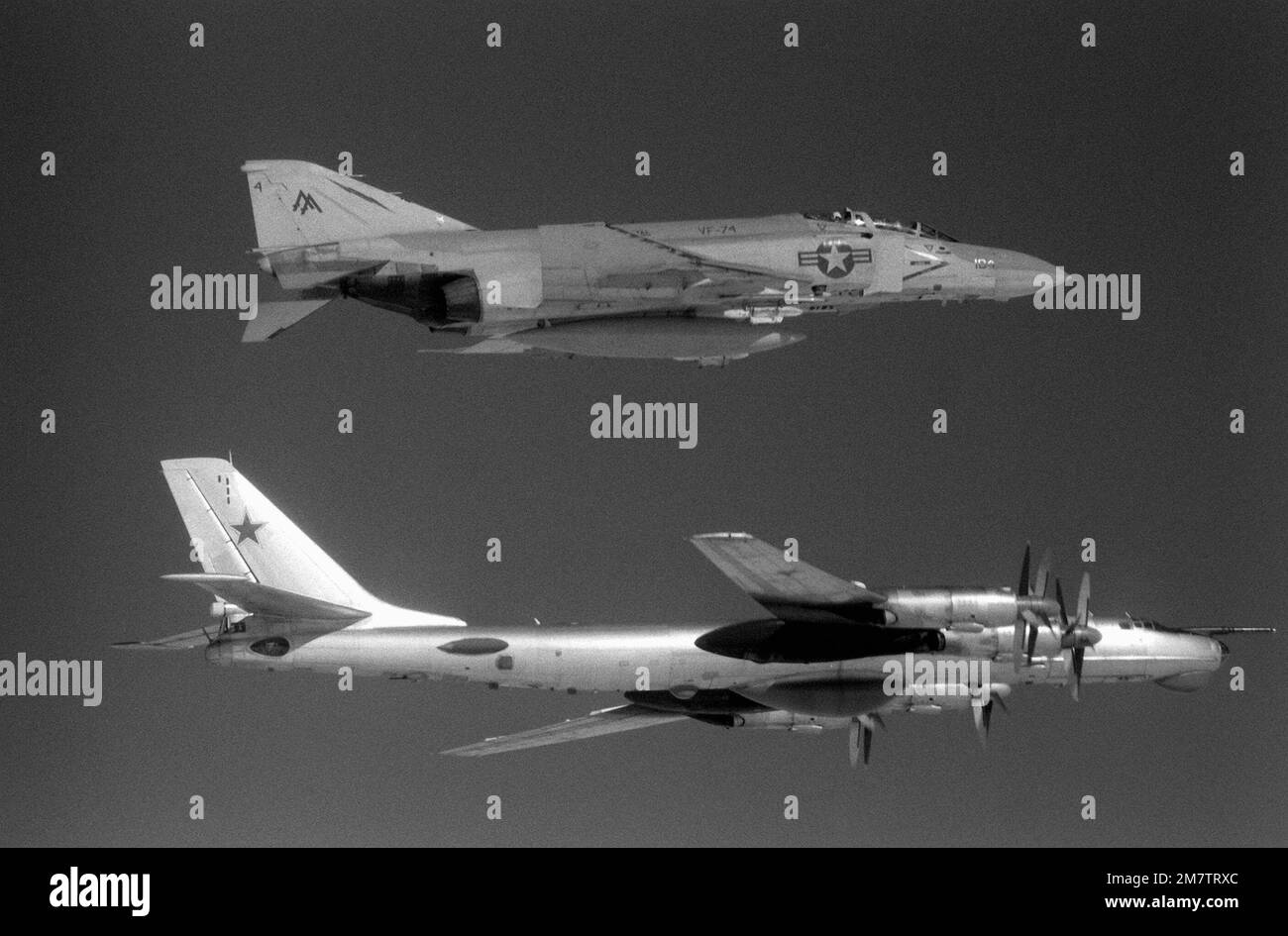 Eine Luft-Luft-Seitenansicht von rechts eines US-amerikanischen Navy F-4 Phantom II Flugzeug, Top, von Fighter Squadron 74 (VF-74) und ein sowjetisches TU-95 Tupolev Bear Flugzeug etwa 42 Meilen vor der Küste von Virginia. Die F-4 begleitet die in Kuba ansässige TU-95, die gerade in die US-Luftwaffenzone eingedrungen ist, um Seeversuche des neuen nuklearbetriebenen Flugzeugträgers CARL VINSON (CVN-70) aus der Vogelperspektive zu betrachten. Land: Atlantik (AOC) Stockfoto
