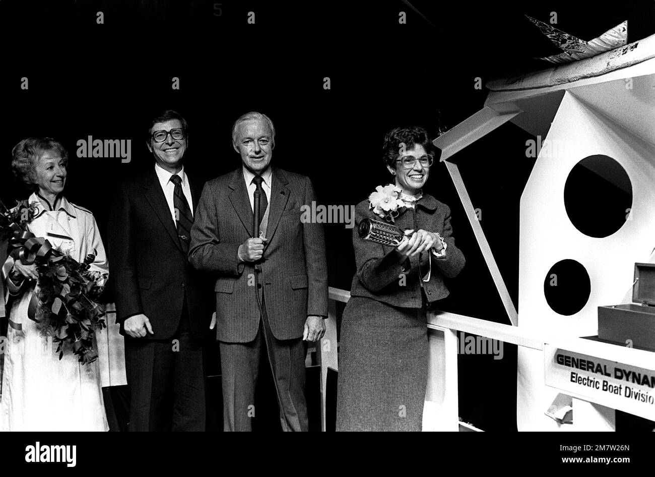 David S. Lewis, Vorstandsvorsitzender der General Dynamics Electric Boat Division, hält das Mikrofon, während Sponsor Nancy L. Domenici während der Startzeremonie die traditionelle Flasche Champagner am Bug des nuklearbetriebenen Angriffs-U-Boots ALBUQUERQUE (SSN-706) zerbricht. Sen. Pete V. Domenici, R-New Mexico, zweiter von links, schaut zu. Basis: U-Boot-Stützpunkt, Groton Bundesstaat: Connecticut (CT) Land: Vereinigte Staaten von Amerika (USA) Stockfoto