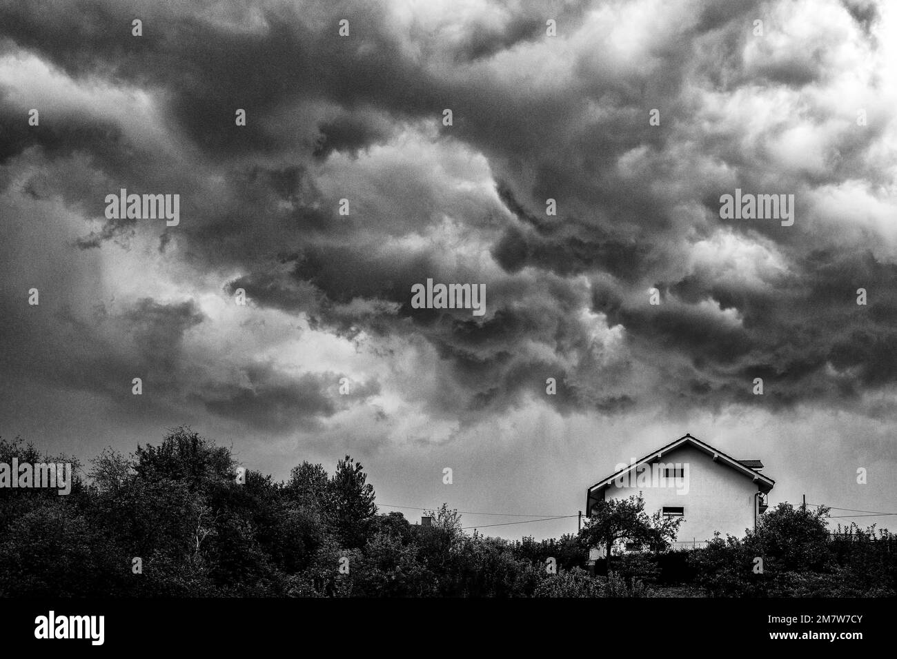 Dunkle, stürmische Wolken über dem Haus auf dem Hügel Stockfoto