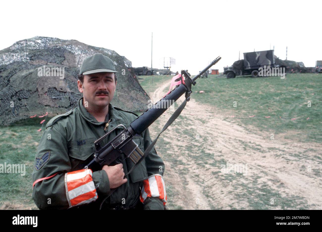 SST Frank Oros, bewaffnet mit einem M-16A1-Gewehr, ist der unkommissionierte Offizier, der während der Übung UREX '82 für die Mobilität zuständig ist. Das rote Armband zeigt, dass er die Erlaubnis hat, scharfe Munition zu transportieren. Betreff Betrieb/Serie: UREX '82 Basis: Bad Krueznach Land: Westdeutschland (FRG) Stockfoto