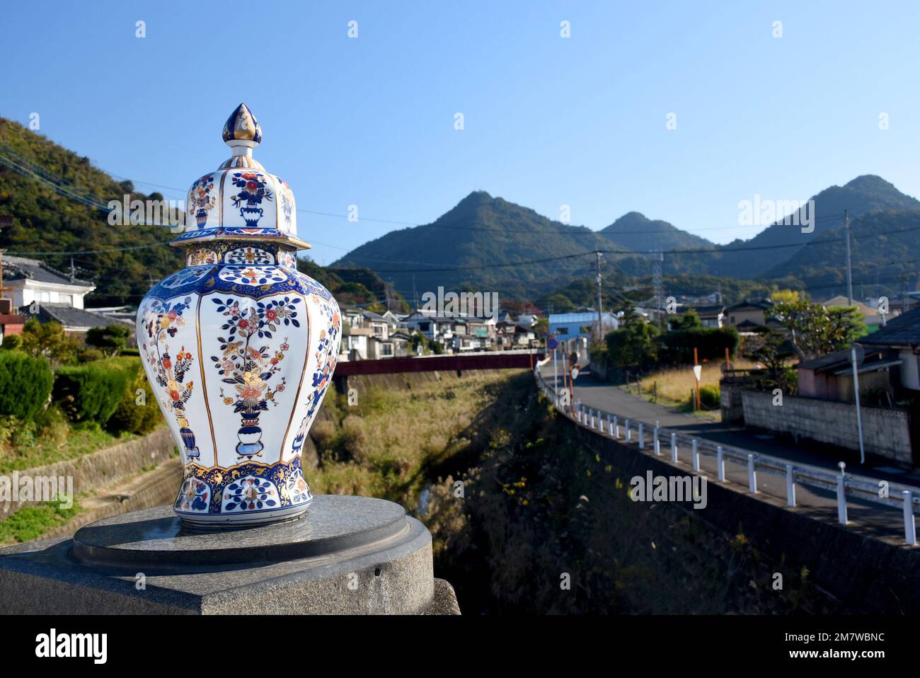 Eine Porzellanvase im traditionellen japanischen Imari-Stil - Rot, Blau und Gold, malerische Landschaft der Stadt Arita im Hintergrund Stockfoto