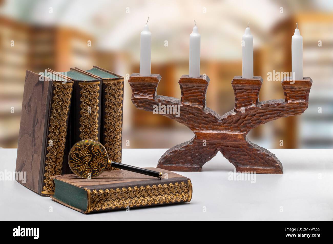 Antike Bücher mit einer Lupe und einem antiken Kerzenhalter aus Holz auf einem hellen Tisch isoliert über abstrakter, verschwommener Bibliothek. Universität, Geschichte Stockfoto
