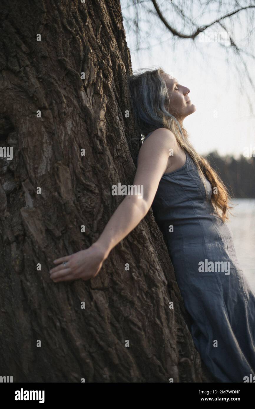 Nahaufnahme einer Frau, die sich spirituell mit einem Weidenbaum-Porträtbild verbindet Stockfoto