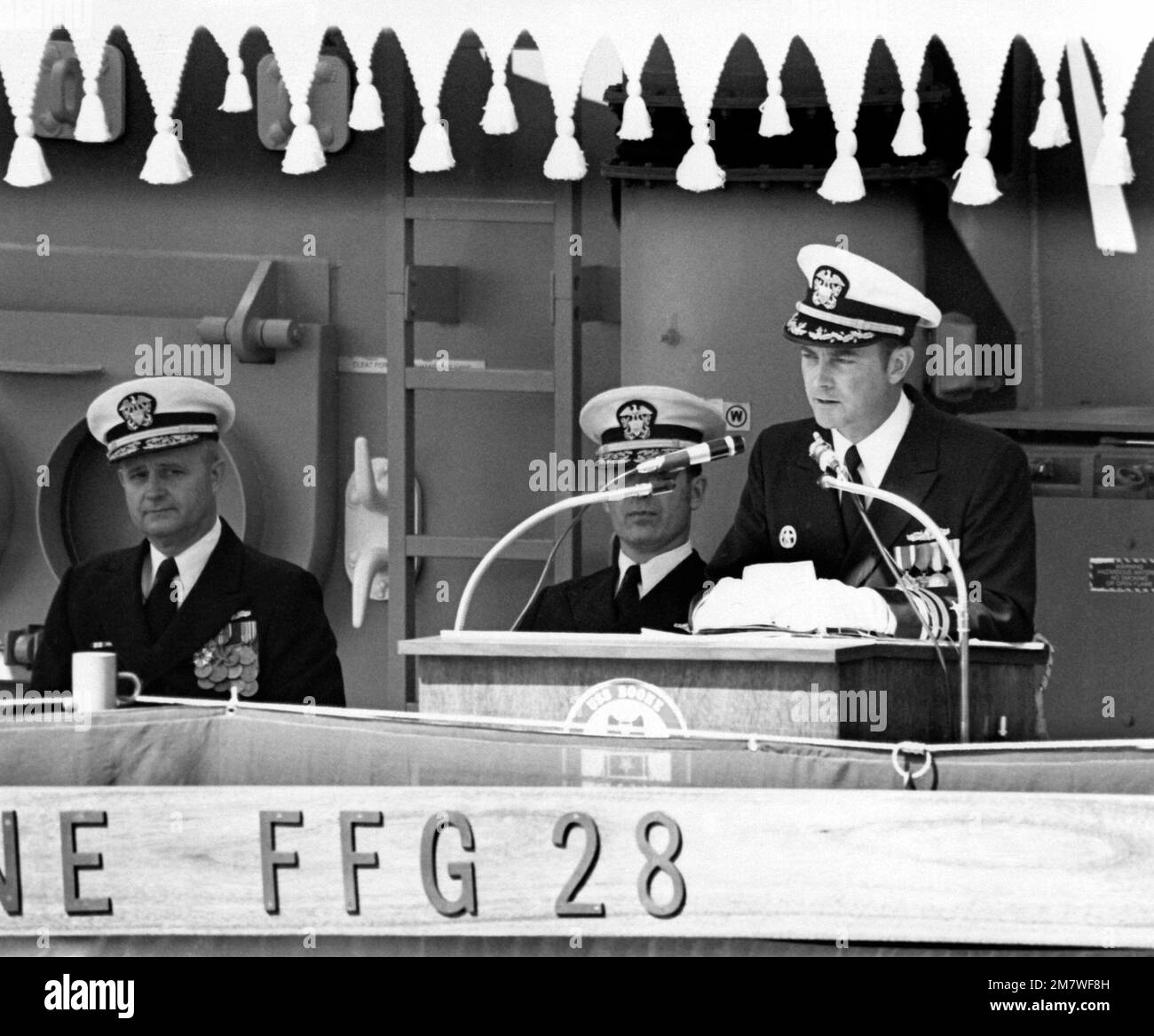 CDR C.A. LaVarre, kommandierender Offizier der geführten Raketenfregatte USS BOONE (FFG-28), spricht während der Inbetriebnahmezeremonie für das Schiff. Hinter ihm sitzt RADM F.C. Johnson, Left und RADM J.D. Williams. Basis: Seattle Staat: Washington (WA) Land: Vereinigte Staaten von Amerika (USA) Stockfoto