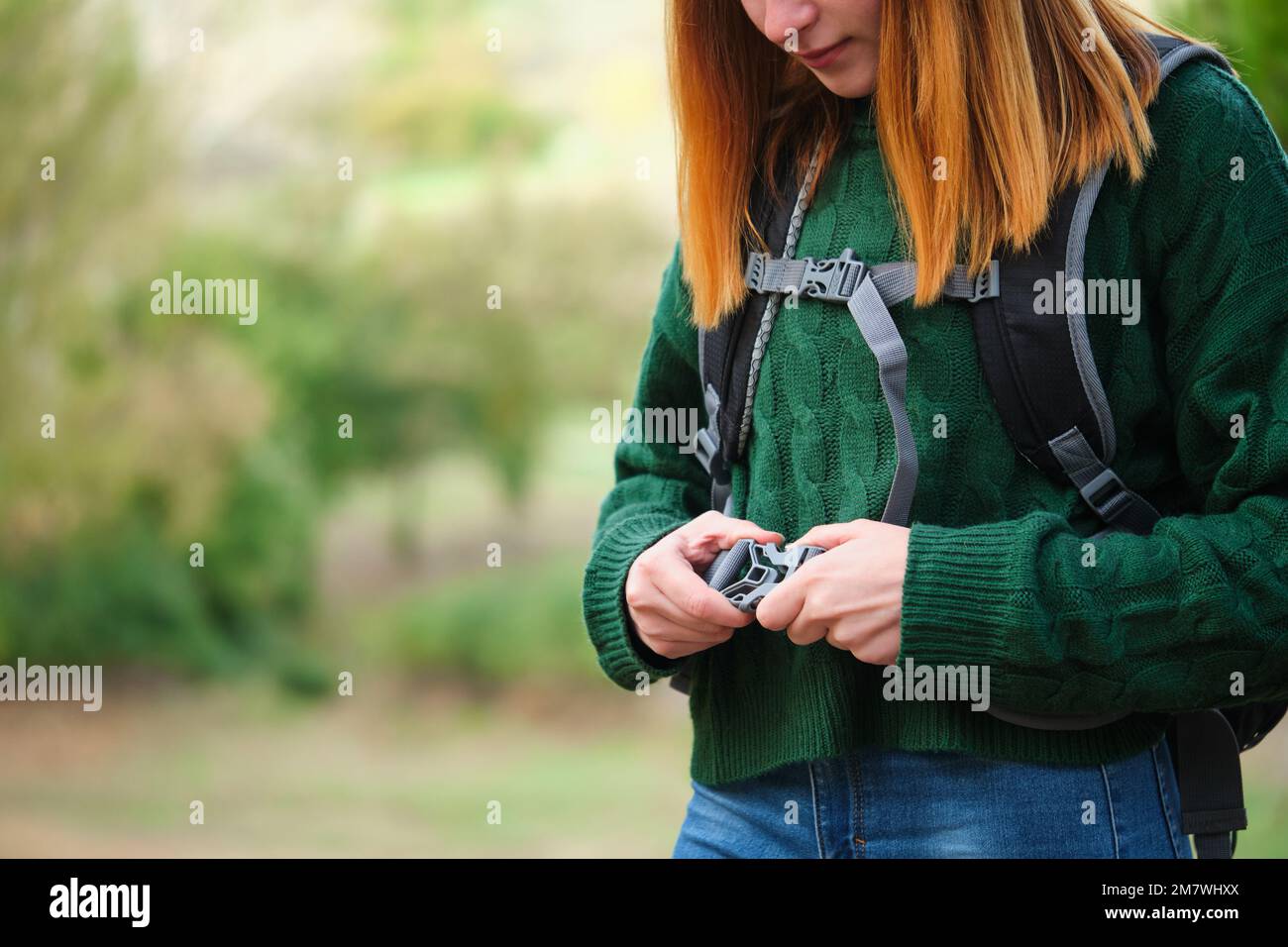 Nahaufnahme einer jungen, rothaarigen Wanderer, die einen Rucksackgurt im Berg befestigt. Stockfoto