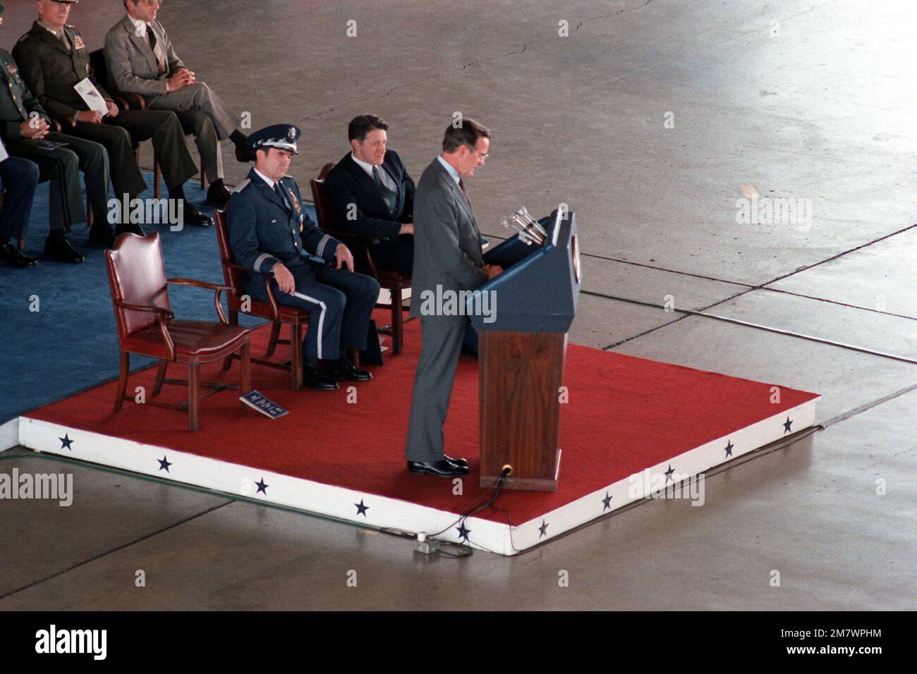 Vizepräsident George Bush spricht mit Ehrengästen während der Ruhestandszeremonie für GENERAL David C. Jones, Vorsitzender des Joint Chiefs STAFF. GEN Jones und Verteidigungsminister Caspar Weinberger sitzen hinter dem Vizepräsidenten. Basis: Luftwaffenstützpunkt Andrews Bundesstaat: Maryland (MD) Land: Vereinigte Staaten von Amerika (USA) Stockfoto