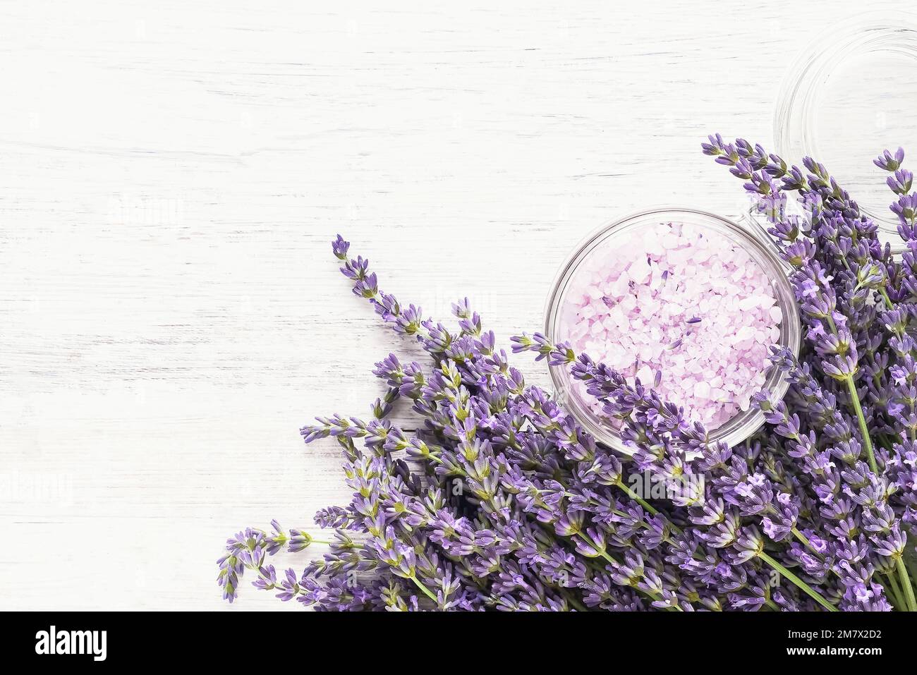 Lavendel Aroma Badesalz und Lavendelblüten auf weißem Holzhintergrund. Spa, Hautpflegekonzept. Draufsicht, Kopierbereich. Selektiver Fokus Stockfoto
