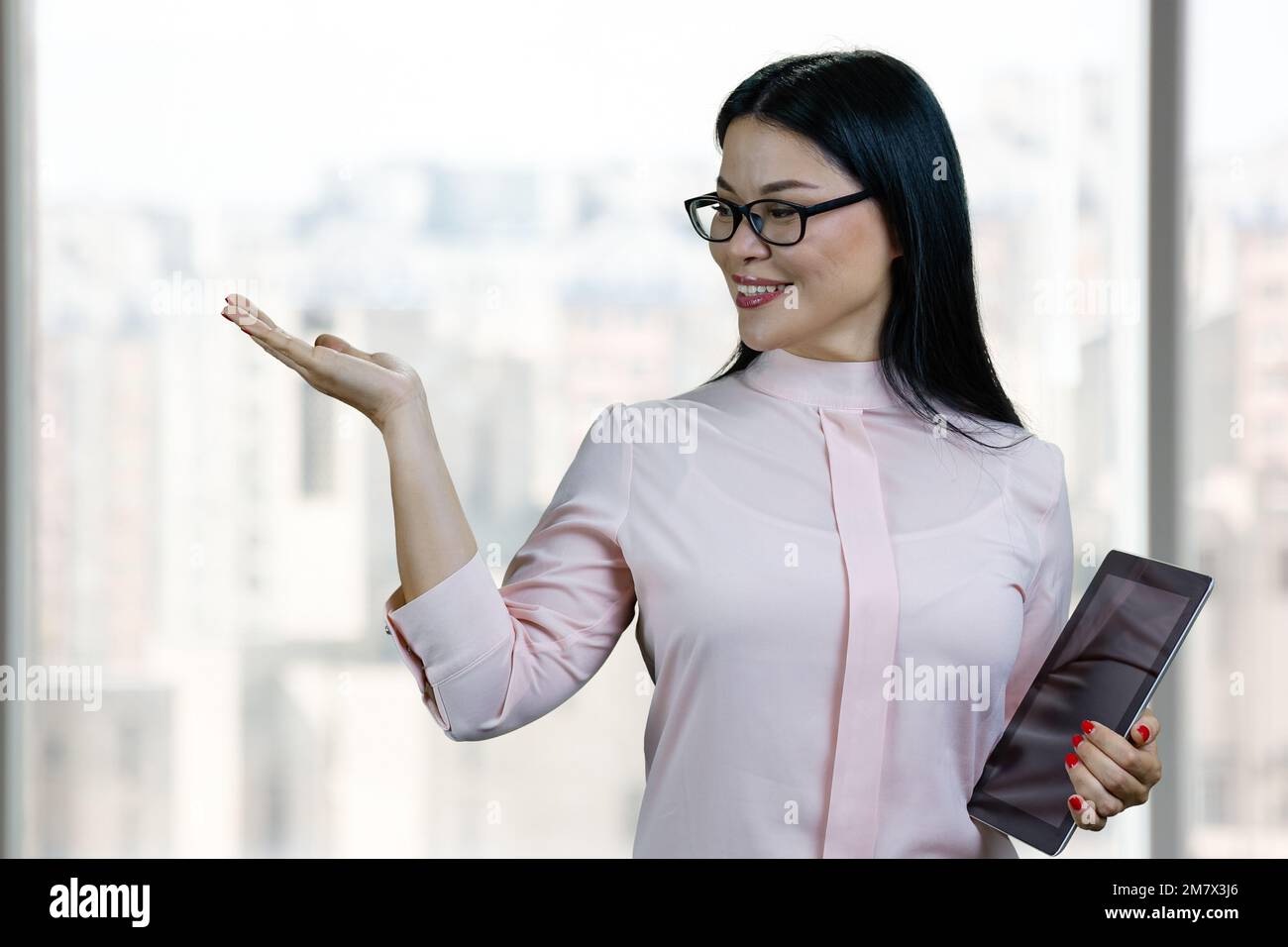 Porträt einer jungen asiatischen Geschäftsfrau mit Tablet-pc und Kopierbereich. Verschwommener Hintergrund für Innenfenster. Stockfoto