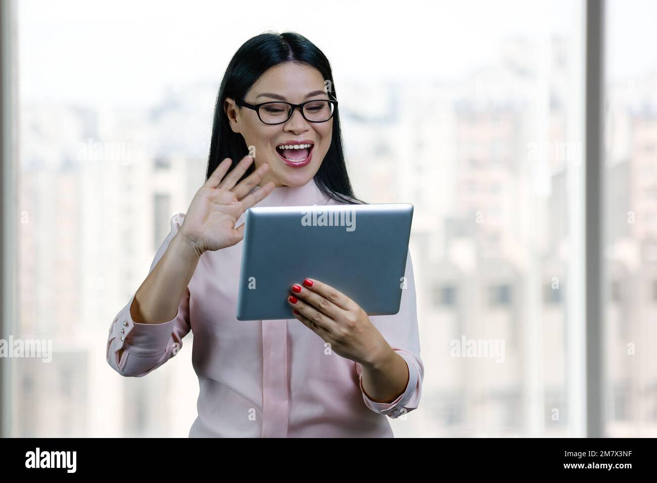 Eine junge asiatische Geschäftsfrau über einen Tablet-pc. Verschwommene Fenster im Hintergrund. Stockfoto