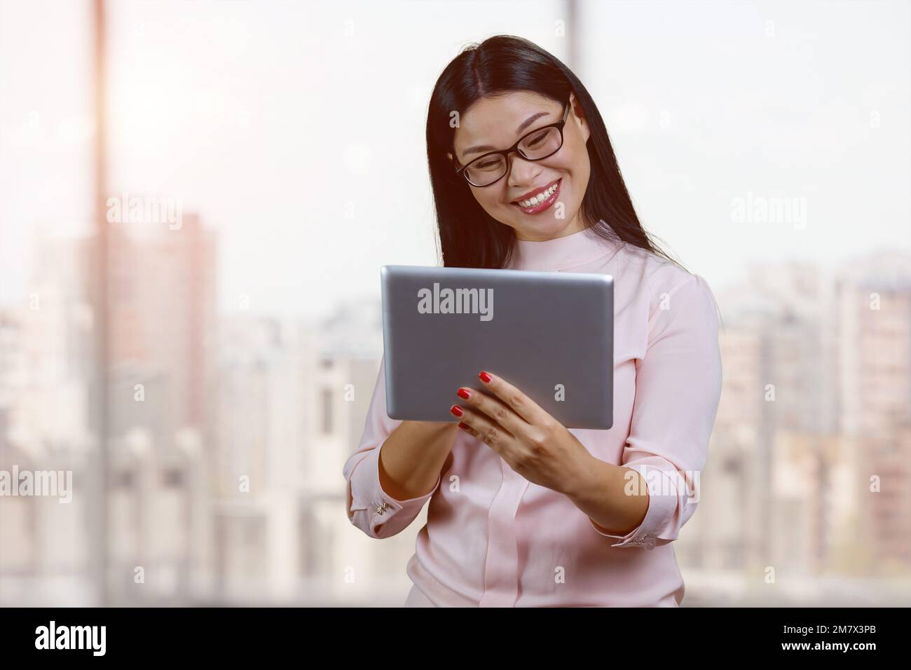 Porträt einer lächelnden jungen asiatischen Geschäftsfrau mit Brille. Background mit Innenfenstern. Stockfoto