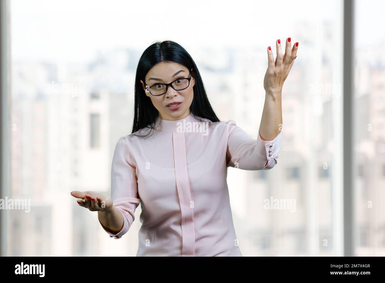 Das Porträt einer ausdrucksstarken asiatischen Geschäftsfrau ist aktiv. Hintergrund für verschwommene Fenster. Stockfoto