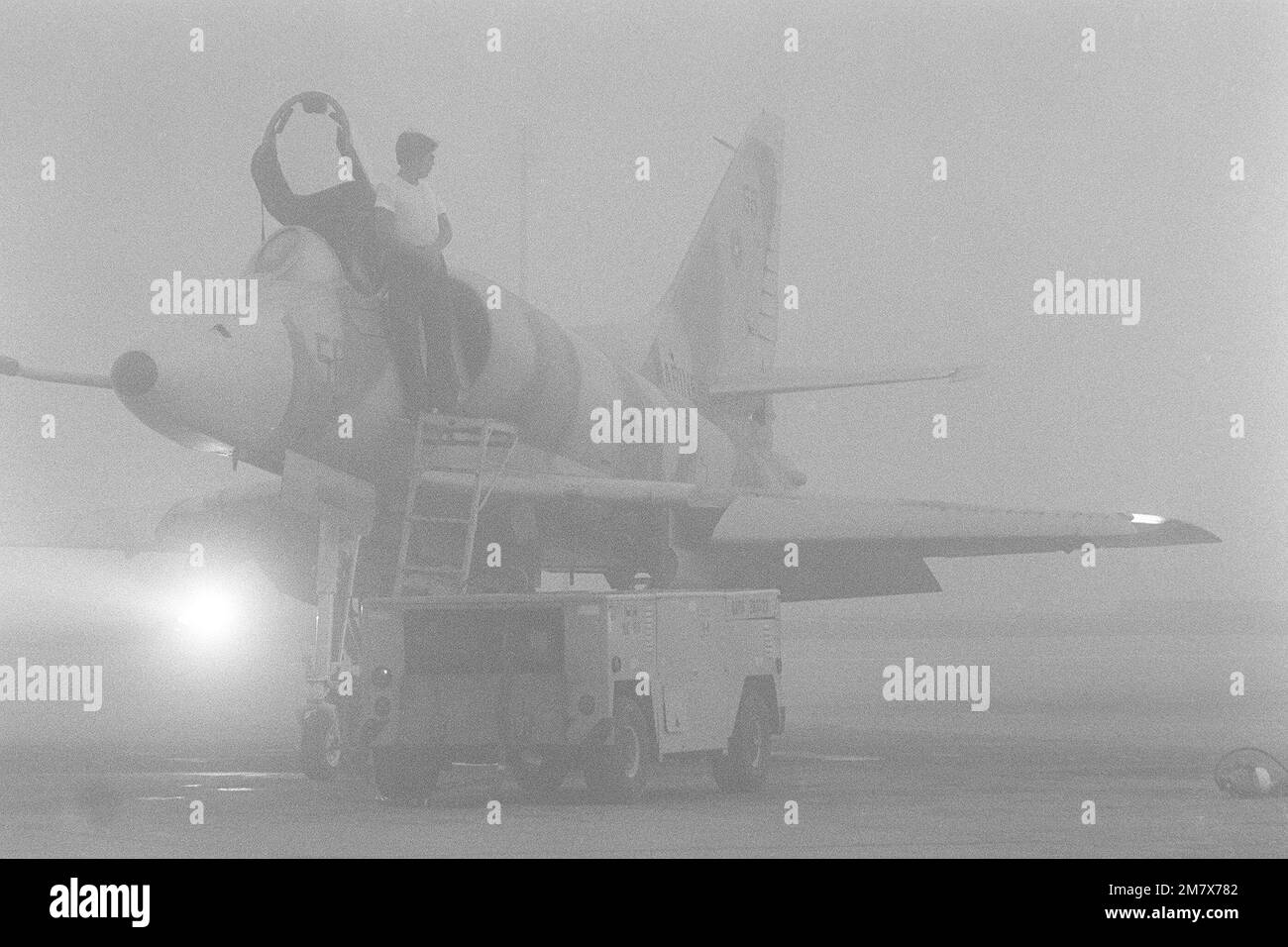 Schwerer Nebel bedeckt die Fluglinie, da ein Navy Fighter Weapons School A-4 Skyhawk Gegenflugzeug für eine morgendliche Mission vorbereitet ist. Die als „Top Gun“ bezeichnete Schule bietet Flugmanövering (ACM) für Navy- und Marine Corps-Piloten an. Die A-4 ist in einem Tarnmuster der Luftwaffe des Sowjetblocks bemalt. Basis: Marineflugstation, Miramar Bundesstaat: Kalifornien (CA) Land: Vereinigte Staaten von Amerika (USA) Stockfoto