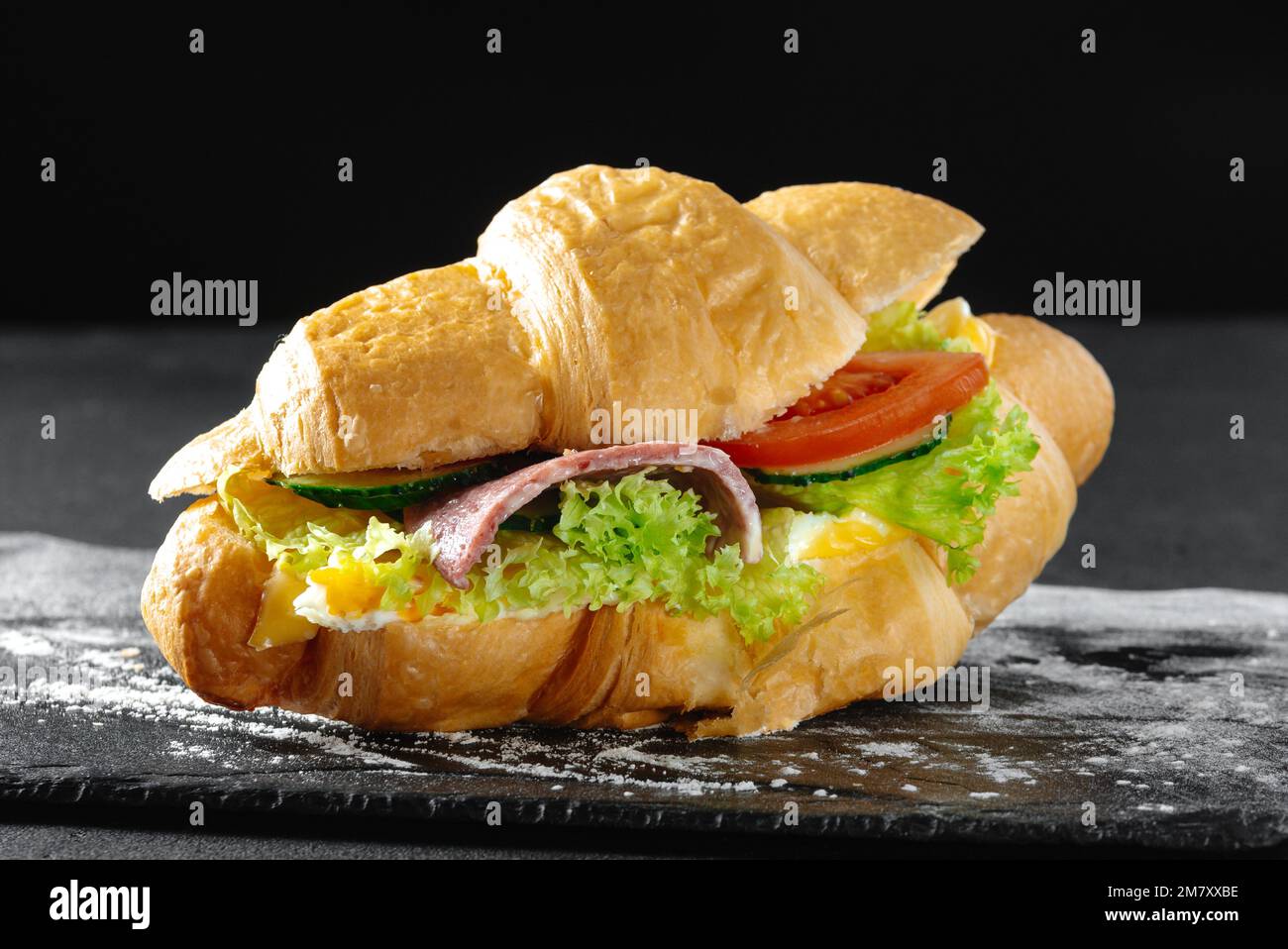 Croissant-Sandwich mit Wurst auf dunklem Hintergrund Stockfoto