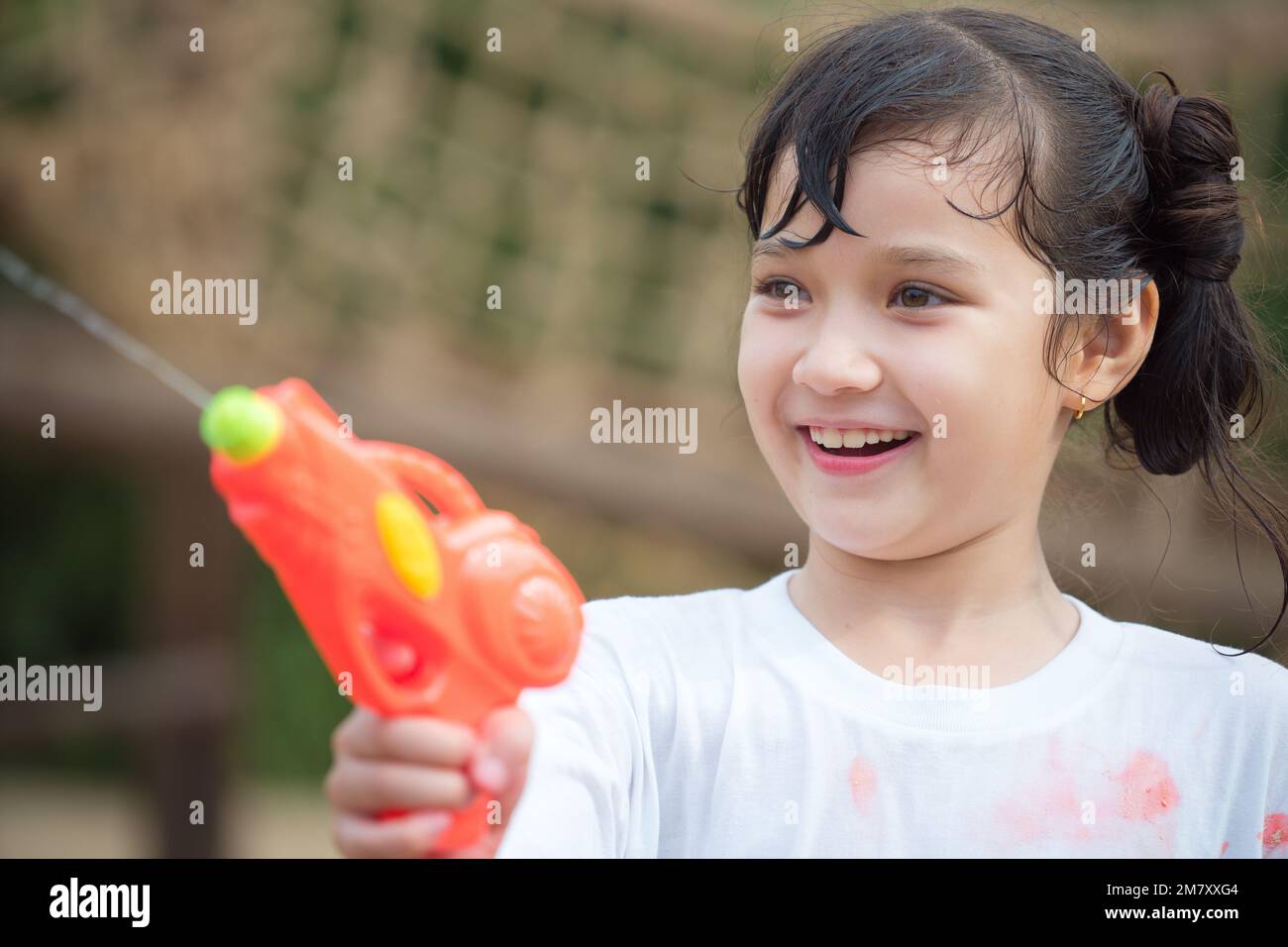Glückliches Kind hat Spaß beim Schießen mit Wasserpistole auf dem Spielplatz im Freien an heißen Sommertagen im Freien. Stockfoto