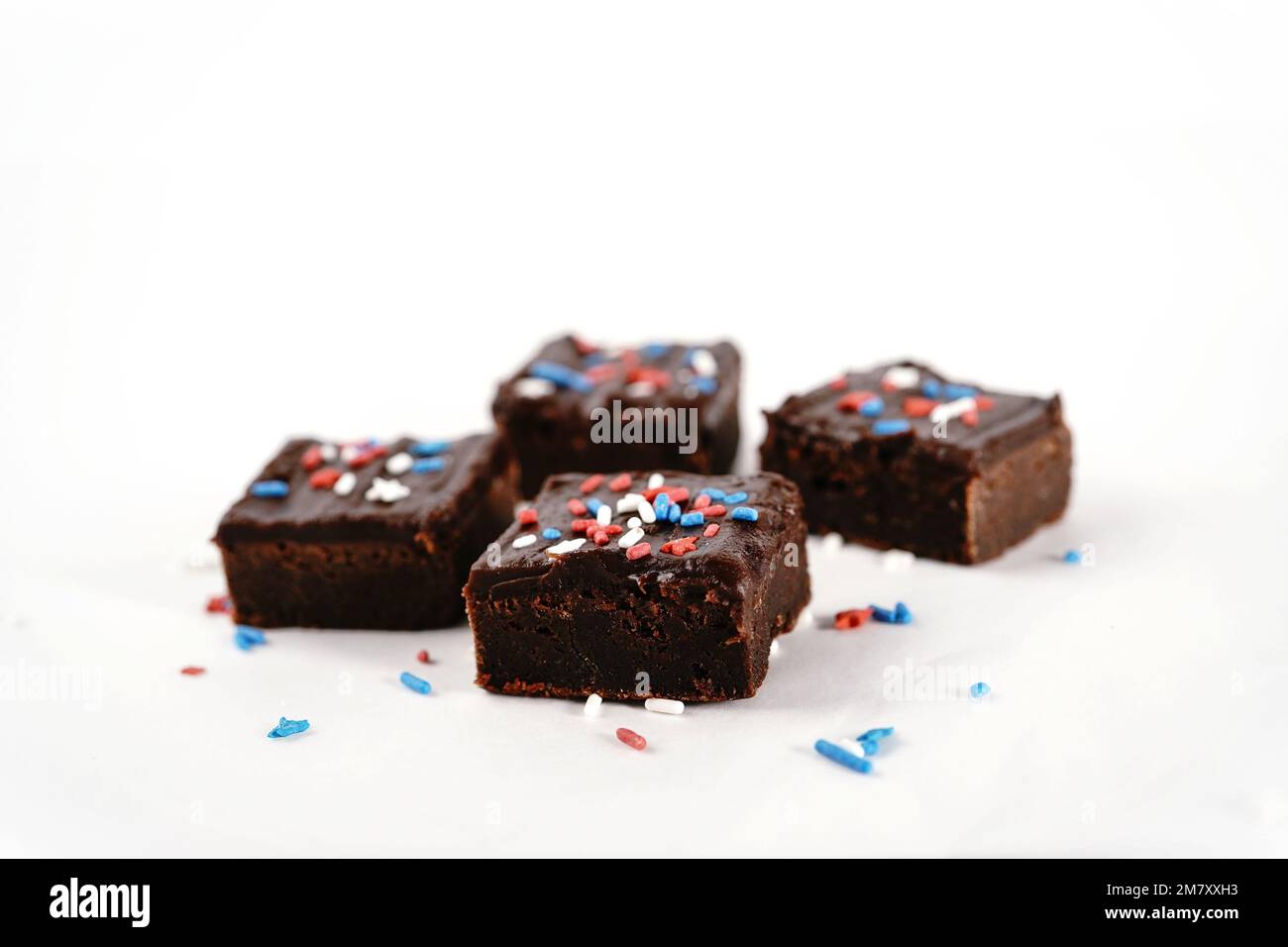 Schokoladen-Karamellbrownies mit patriotischen roten, blauen, weißen Streuseln auf weißem Hintergrund Stockfoto