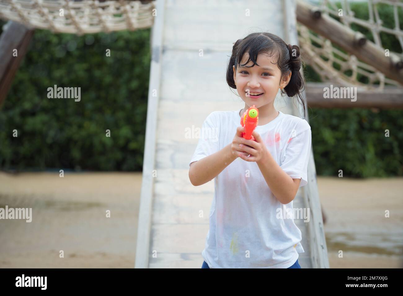 Glückliches Kind hat Spaß beim Schießen und Schießen mit Wasserpistole auf dem Spielplatz im Freien an heißen Sommertagen im Freien. Stockfoto