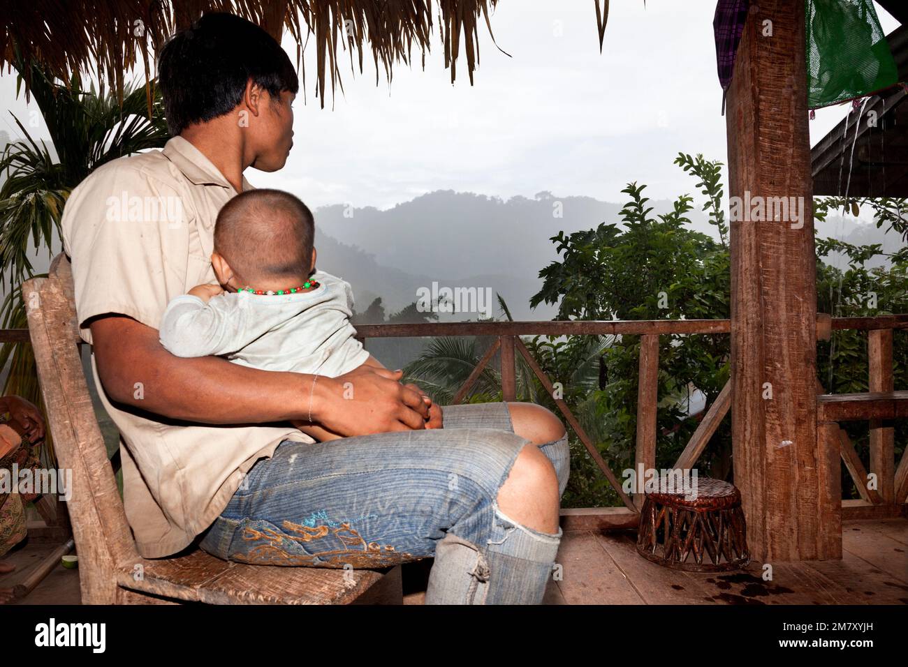 Luang Nam Tha, Laos, 19. Juli 2009. In einem Dorf des ethnischen Khamu im Norden von Laos hält ein junger Mann nach einem harten Arbeitstag seinen Sohn beim Watc zum Schlafen Stockfoto