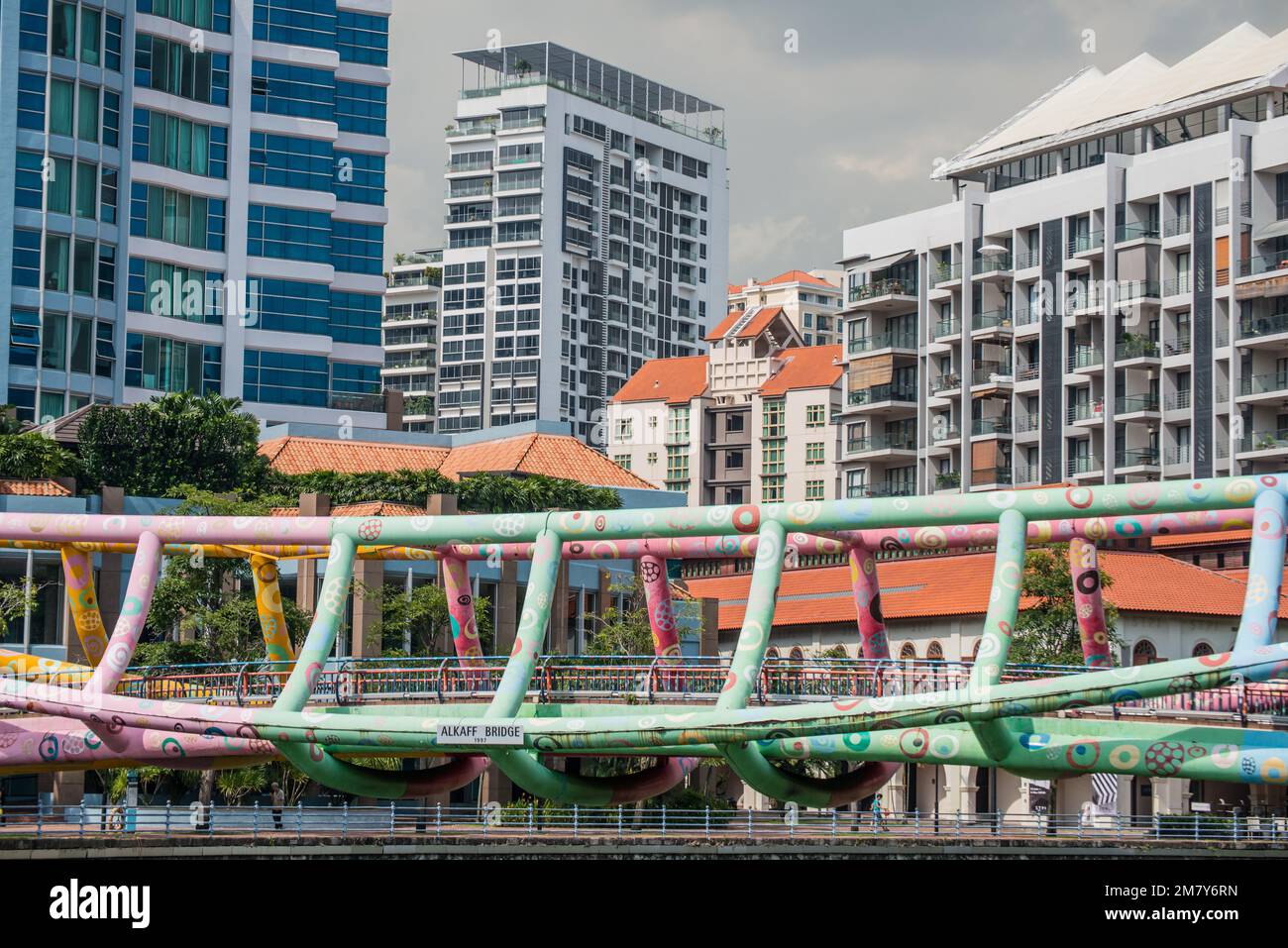 Die Alkaff-Brücke, eine Fußgängerbrücke aus Stahlrohren in Singapur, die sich über den Singapore River am Robertson Quay erstreckt, mit Turmblöcken dahinter Stockfoto