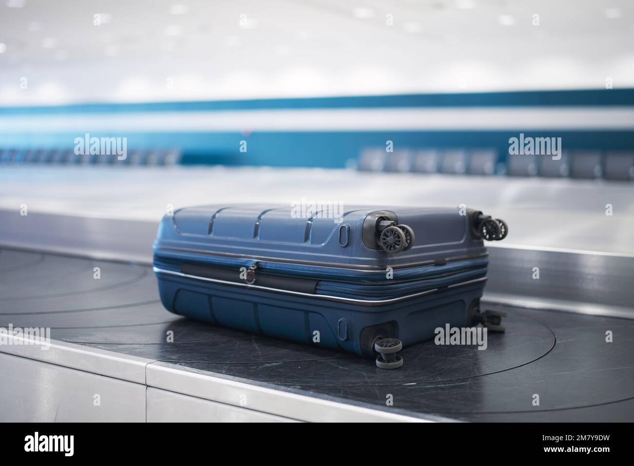 Reisen mit dem Flugzeug. Blauer Koffer auf der Gepäckausgabe im Flughafenterminal. Stockfoto