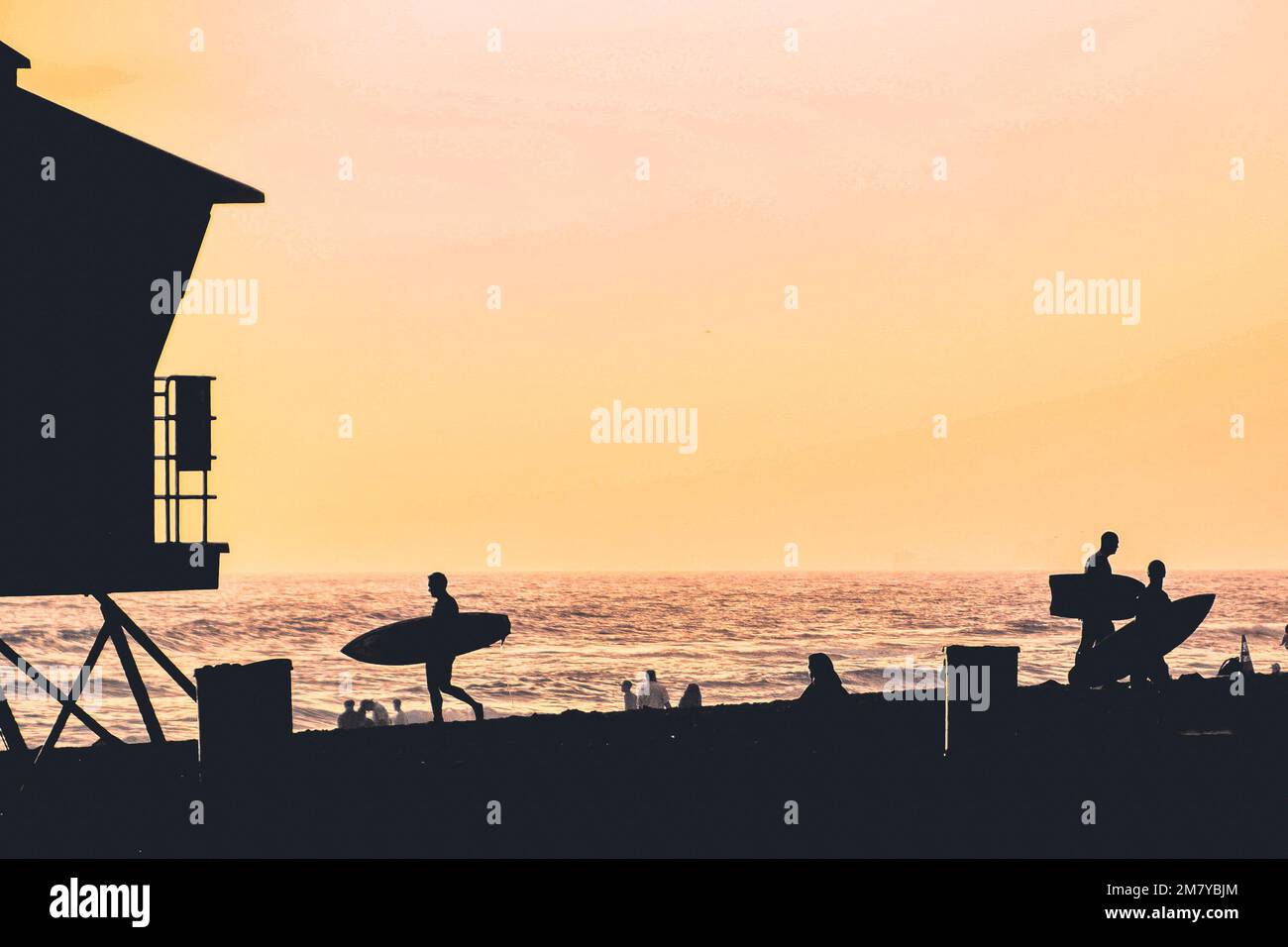 Silhouetten von Surfern am Strand bei Sonnenuntergang in Huntington Beach Stockfoto