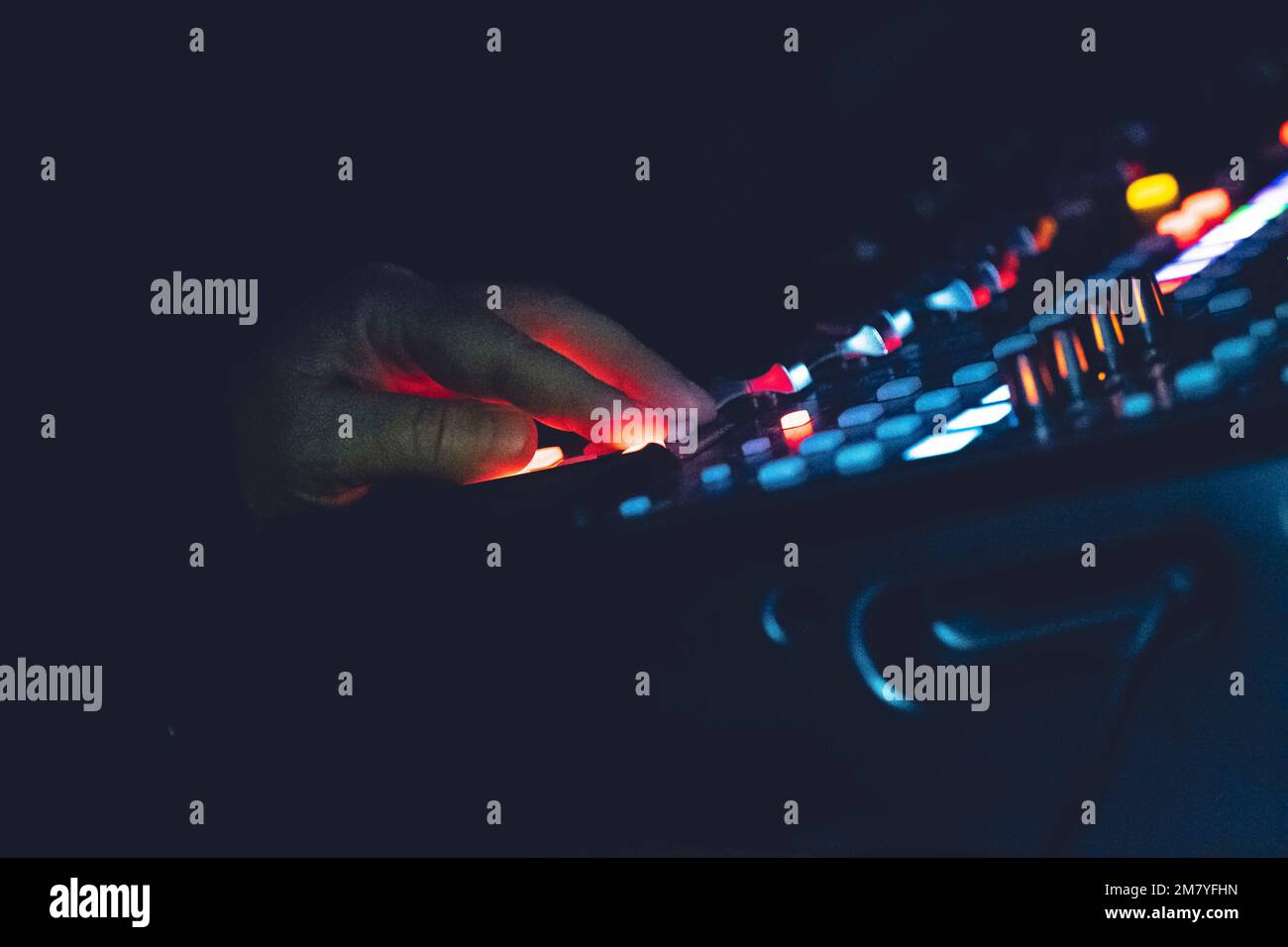 Eine Nahaufnahme einer männlichen Hand auf einem digitalen Soundboard mit leuchtenden Lichtern Stockfoto