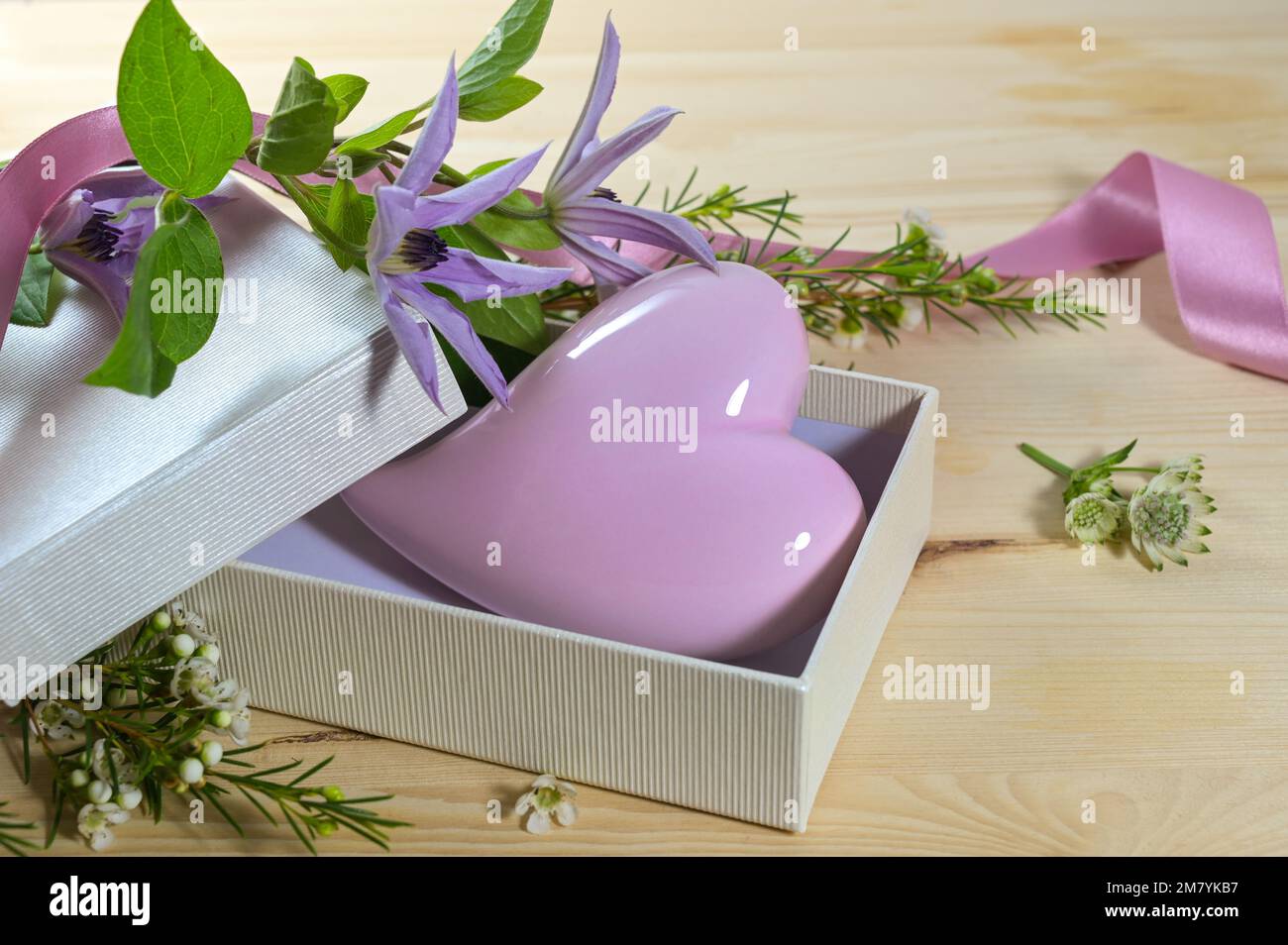 Lavendel-Violett aus Glas in einer offenen Geschenkbox und einige Blumen auf einem Holztisch, Liebessymbol und Grußkartenanordnung zum Valentinstag Stockfoto