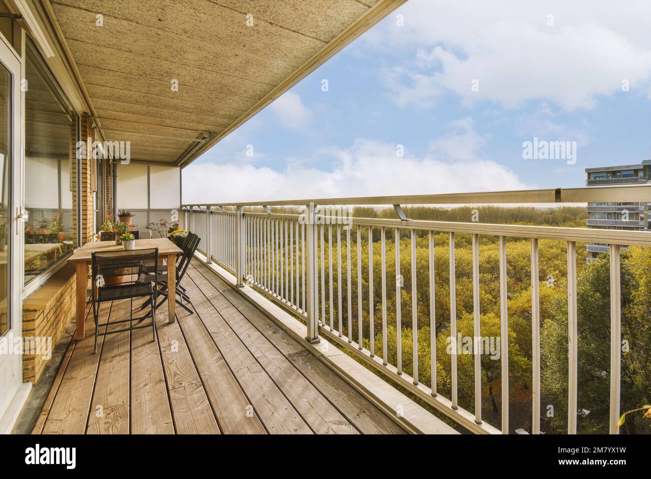 Ein Balkon mit Holzfußboden und weißen Geländern außen, mit Blick auf die Bäume in der Ferne Stockfoto